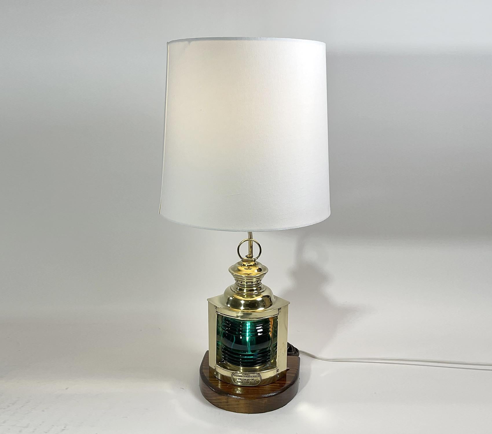 Solid brass ships lantern with Fresnel glass lens. On front of ship lantern is a brass label that read: Chas C. Hutchinson, 152 ST., Boston, Mass. Great early twentieth century lantern, mounted to a wood base. Circa 1925. Beautiful green lens.