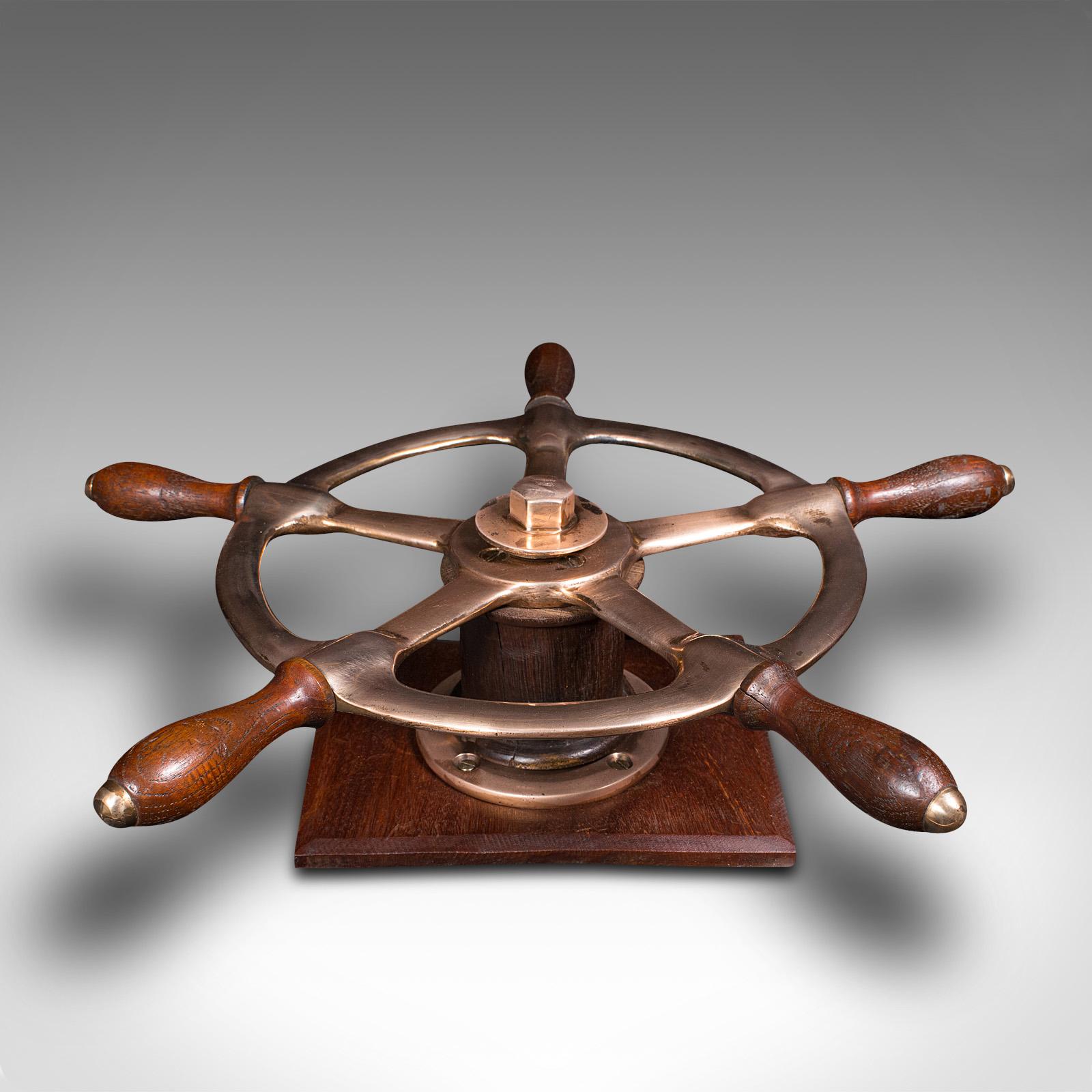 This is a mounted mid-century ship's wheel. An English, bronze and oak decorative maritime helm, dating to the mid-century.

Pleasingly presented wheel with nautical appeal
Displays a desirable aged patina and in good order
Eye-catchingly polished