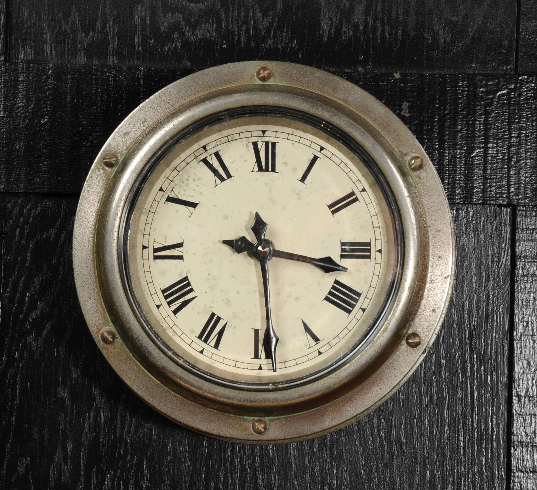 A wonderful, heavy bronze ship or Yacht bulkhead clock. Originally nickel plated, this has worn to a lovely rich brown patina with speckled old plating and green verdigris. A heavy bronze flange holding the thick beveled glass in place with a