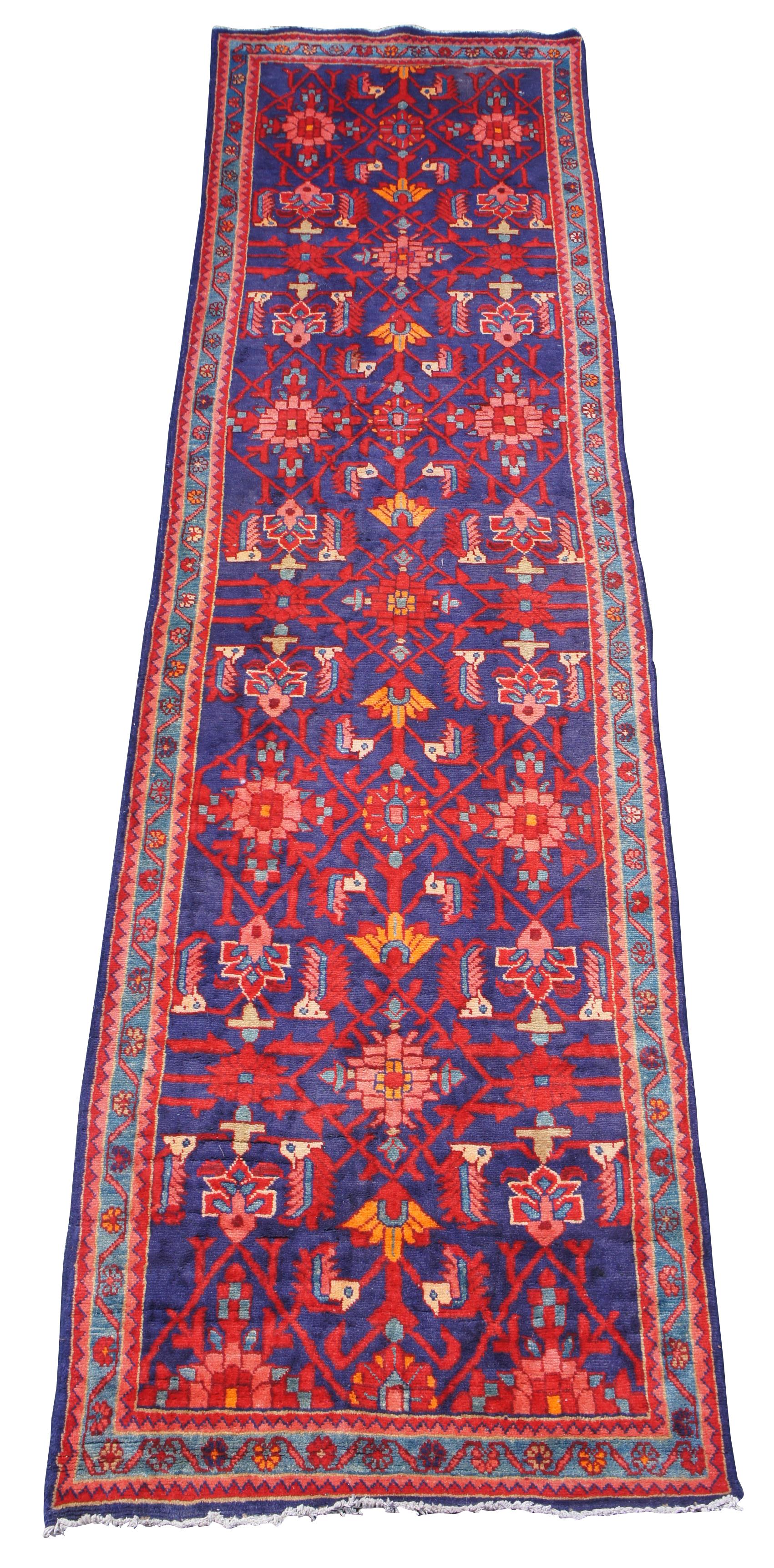 Vintage Shiraz Lori hand knotted Persian rug runner. Features geometric patterns with a field of indigo or purple and blues, orange, cream or beige and pinks. Measures: 14’.
  