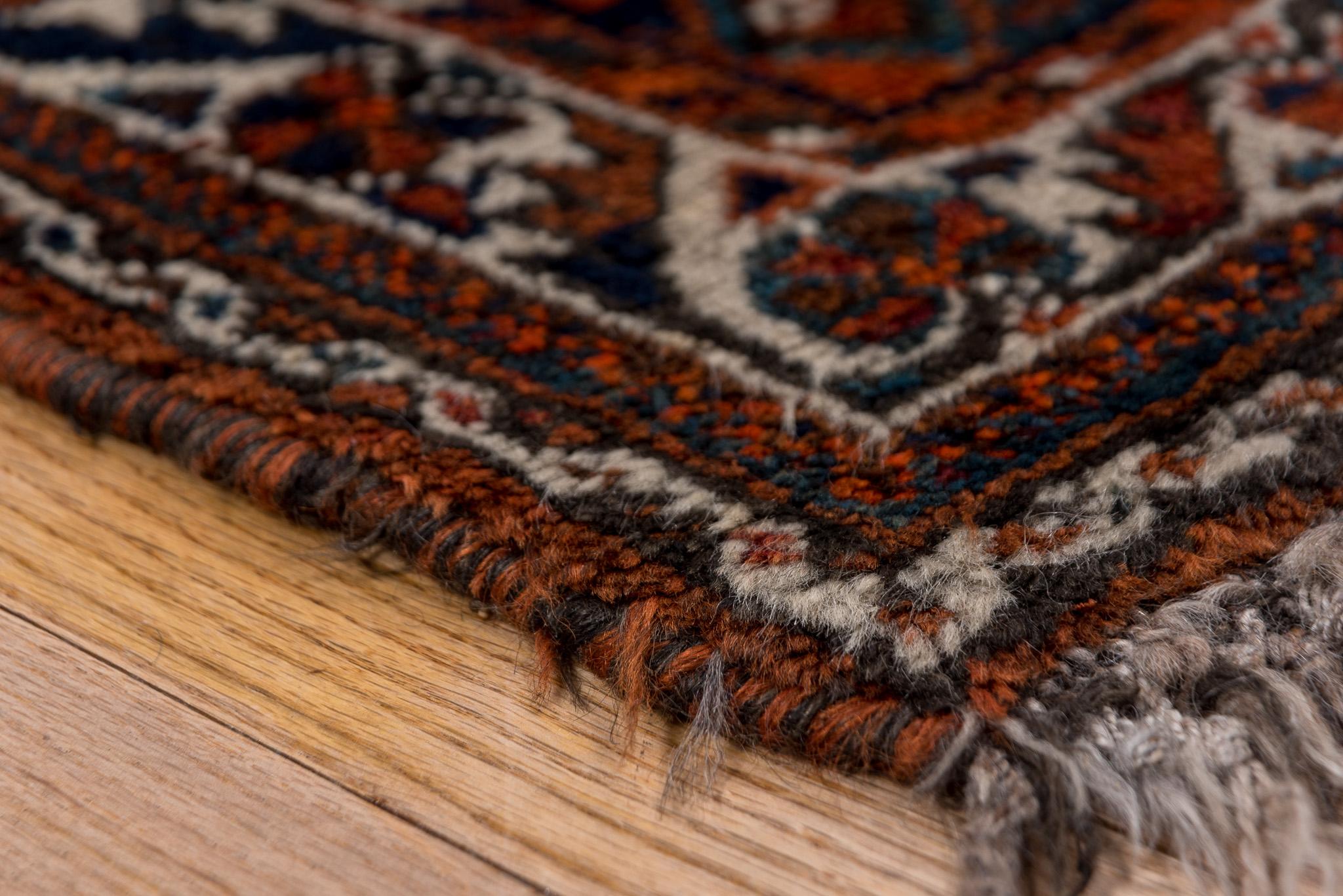 Il s'agit d'un magnifique tapis de Shiraz mesurant 2,8 x 4,3 pieds. Il présente un médaillon central en diamant entouré de motifs tribaux complexes dans des tons chauds et terreux de rouille, de marine et d'ivoire. La texture nouée à la main et le