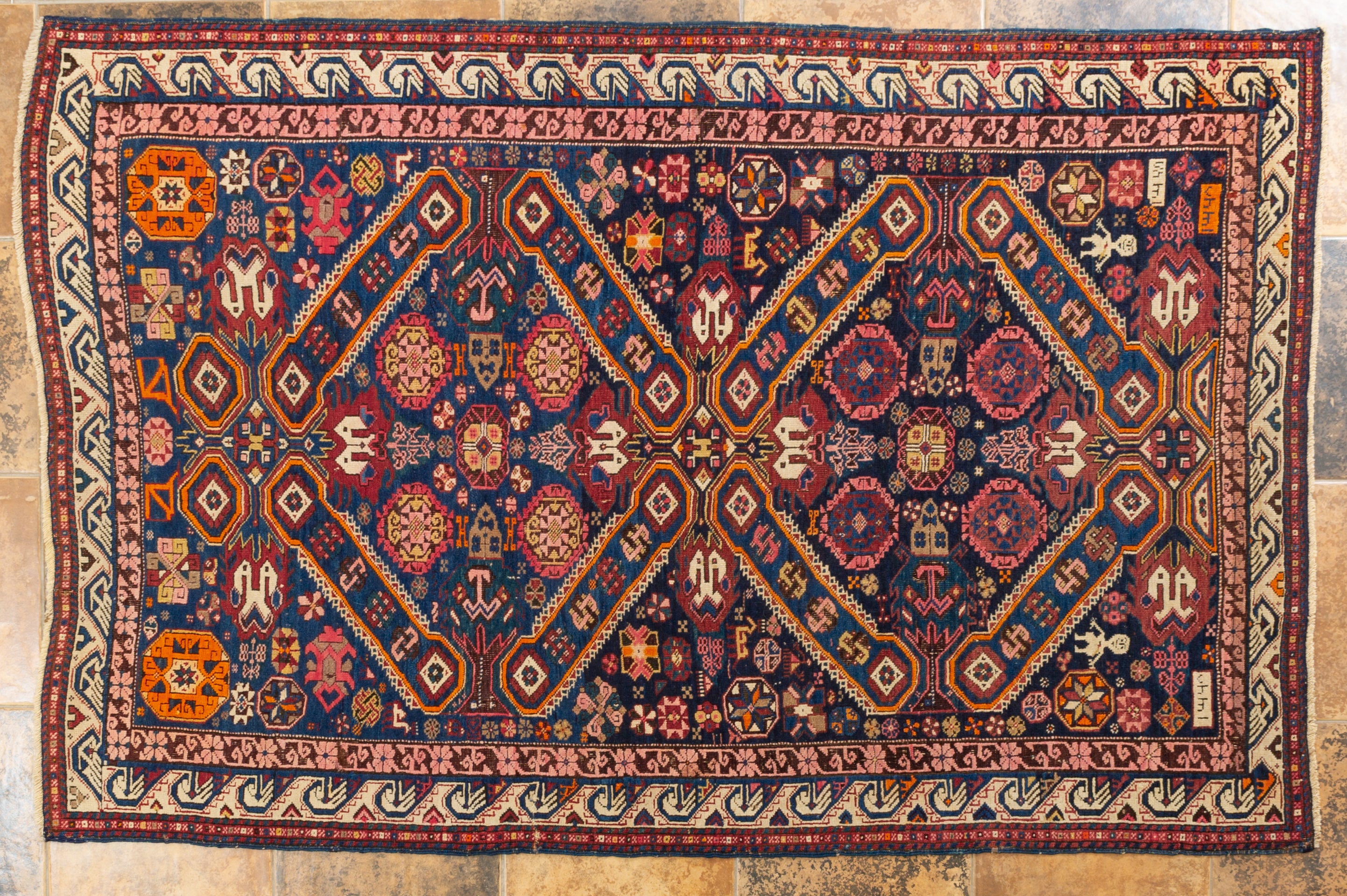 nr. 432 - Antiker SHIRVAN von 1328 (=1910) in schönen Farben auf blauem Grund. Einer der schönsten kaukasischen Teppiche, die ich je gesehen habe. 
Das Feld ist vollständig mit vielen Mustern bedeckt, auch mit kleinen Männerfiguren, die den Weber
