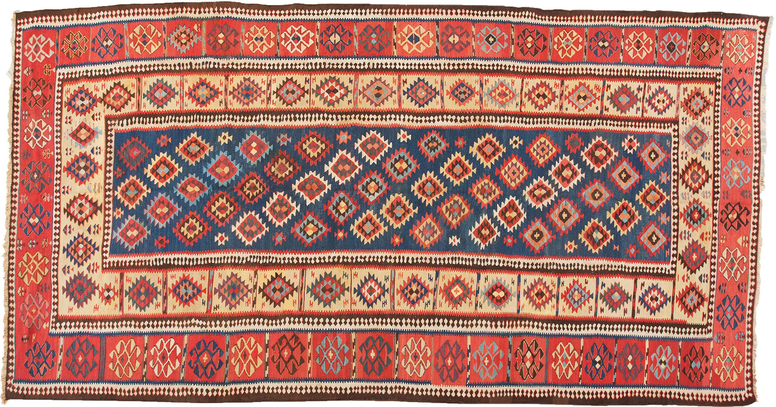 Superbe kilim antique de Shirvan. Le fond bleu est décoré de losanges multicolores entourés d'une bordure jaune clair et d'une belle bordure rouge décorée du motif du mauvais œil. Cette pièce présente une merveilleuse combinaison de couleurs, compte