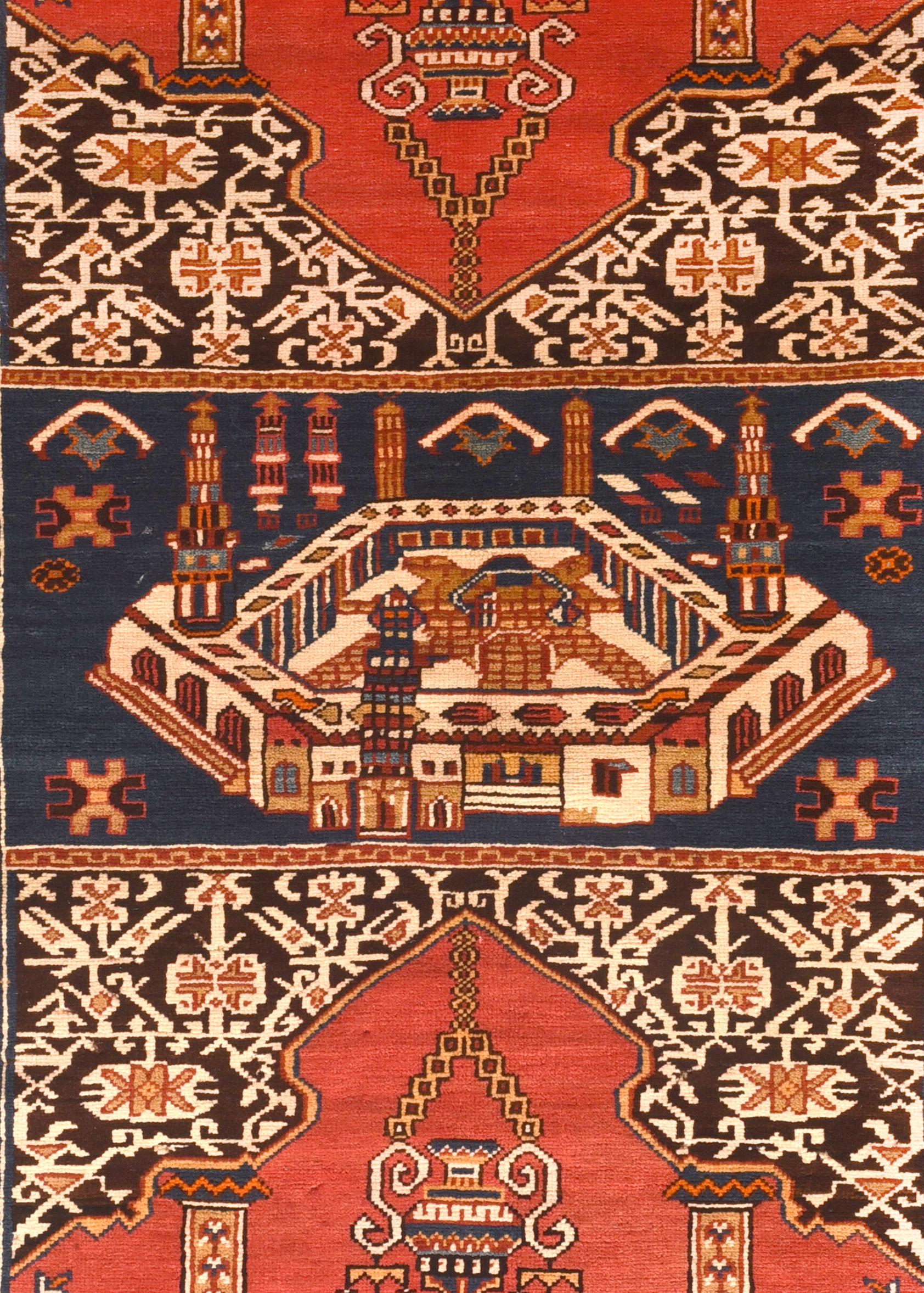 The royal blue central panel shows a semi-perspectival view of the Grand Mosque at Mecca, while the two vertically flanking sections depict flattened, converging Ghiordes-style red prayer niches with columns and suspended lamps. Ivory border of