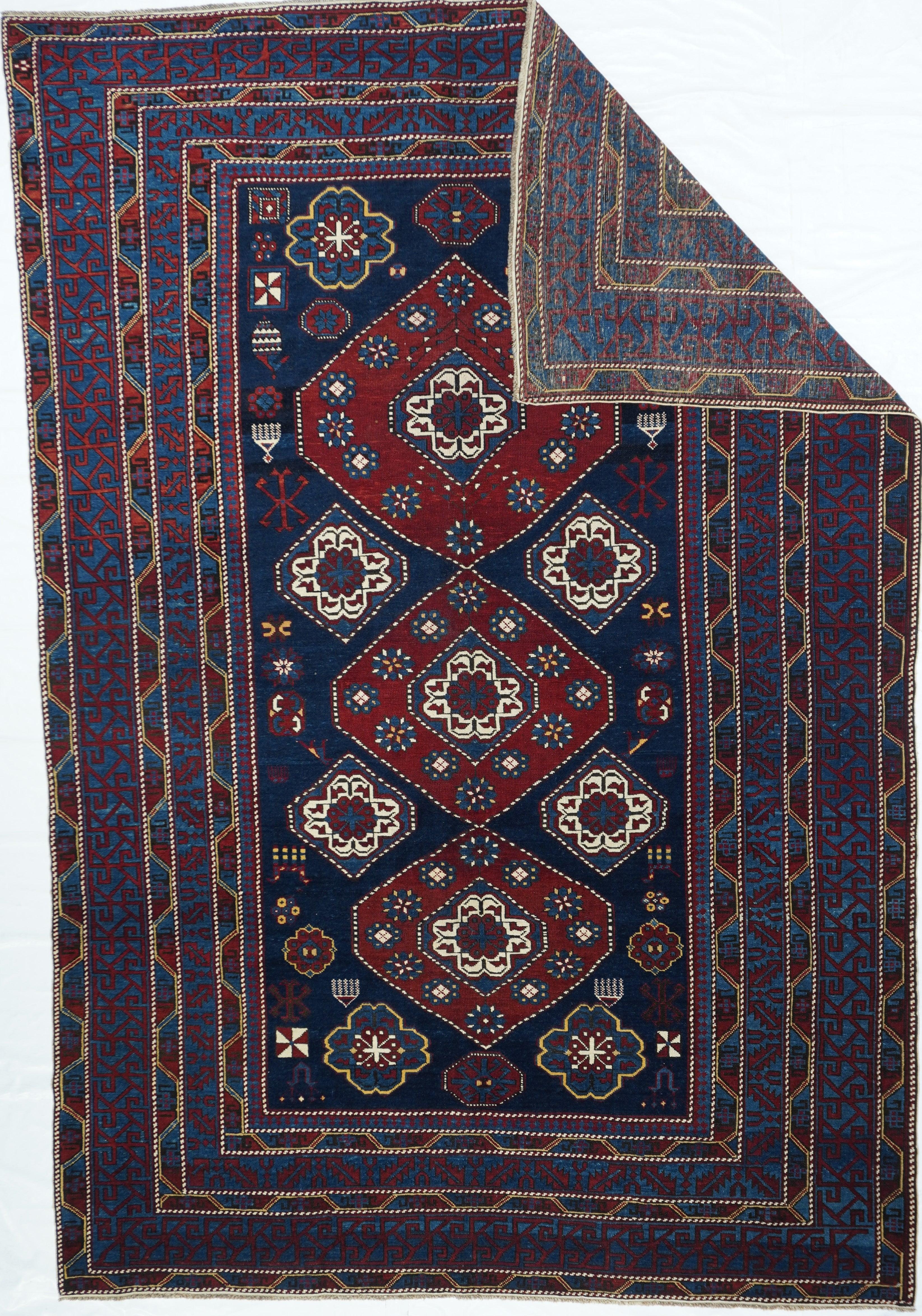 This east Caucasian well-woven scatter is basically a study in blue tones: royal blue for the field and abrashed medium-dark blue in the border system. Three hexagonal red panels enclose each an eight petal ivory rosette, and this motif reappears
