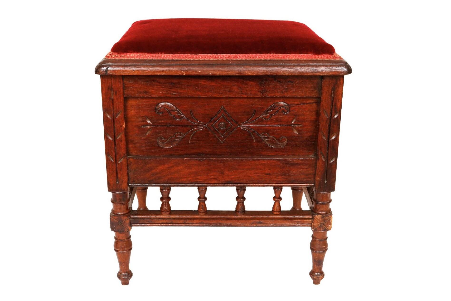 An antique shoe shine box stool. The hinged lid is covered in red velvet finished with a red gimp. Sides are decorated with simple Eastlake carvings. Inside is housed a cast iron shoe shine foot rest cast with a floral motif and a central love