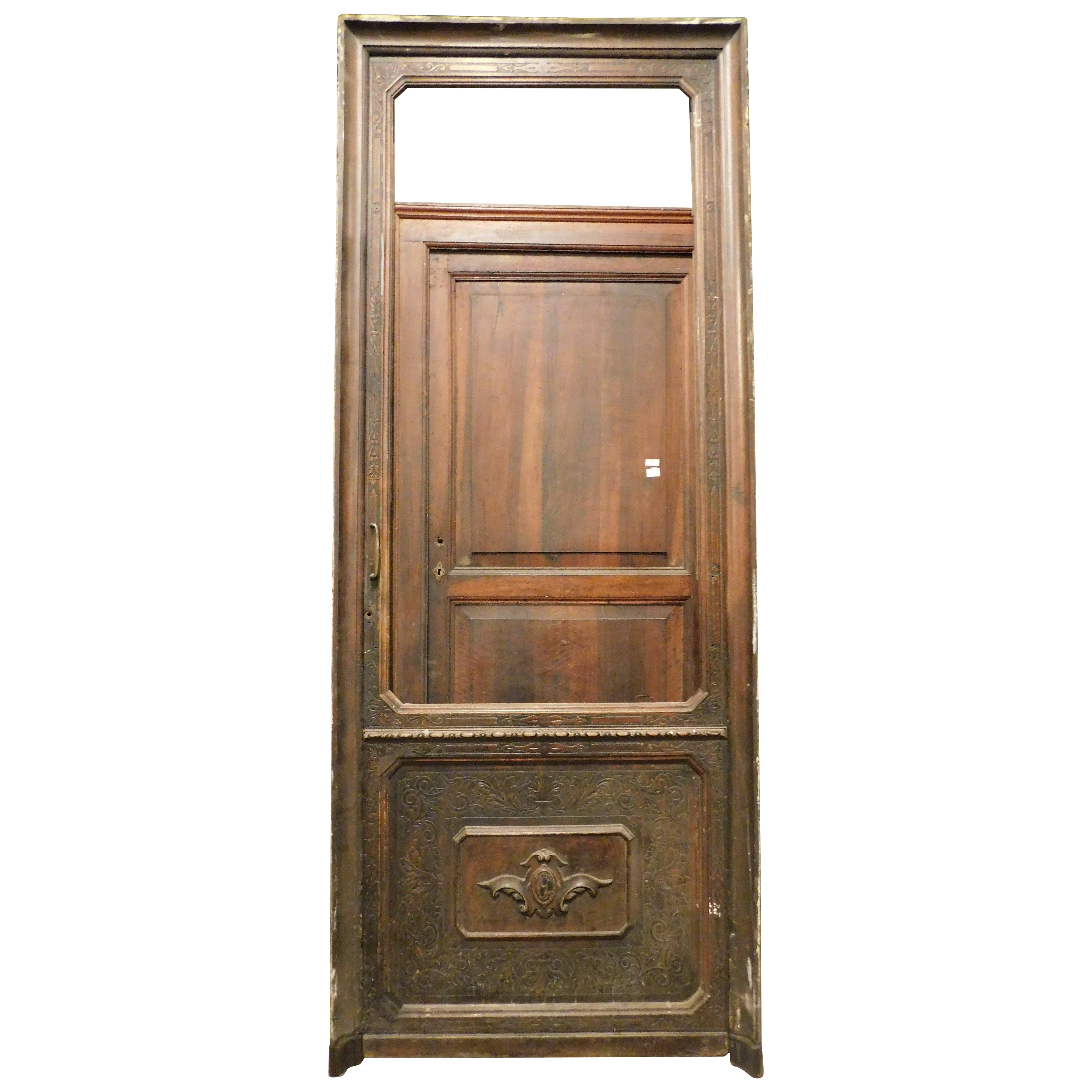 Ancienne porte de magasin en noyer, façade de magasin historique avec panneau sculpté, complète avec cadre et ferronnerie, à reglacer et serrure à fixer, construite dans les années 1800 pour un lieu situé dans le centre historique de