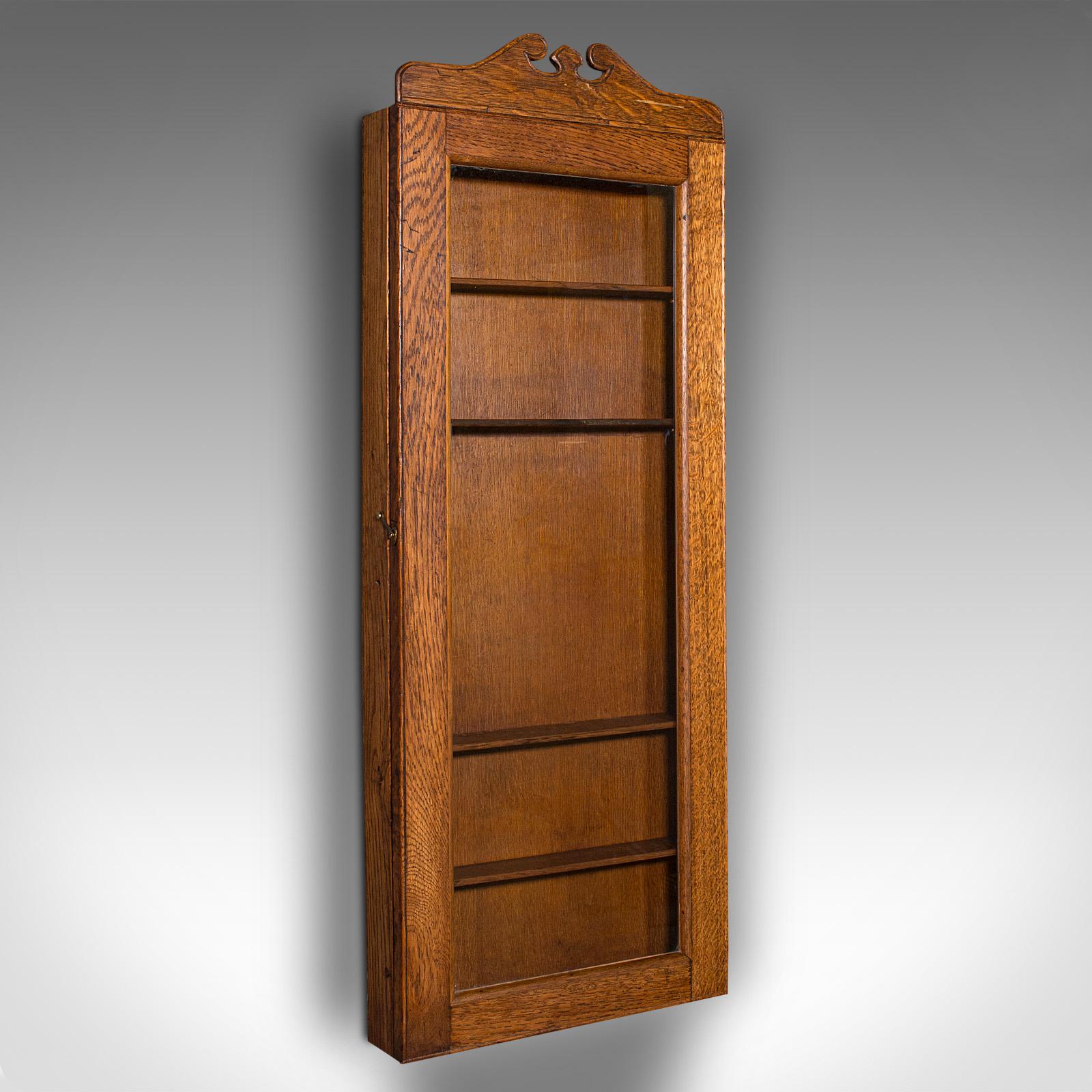 This is an antique shop's display cabinet. An English, oak showcase with glazed door, dating to the Edwardian period, circa 1910.

Slender proportion with a pleasingly tall profile, ideal for a small collection
Displays a desirable aged patina