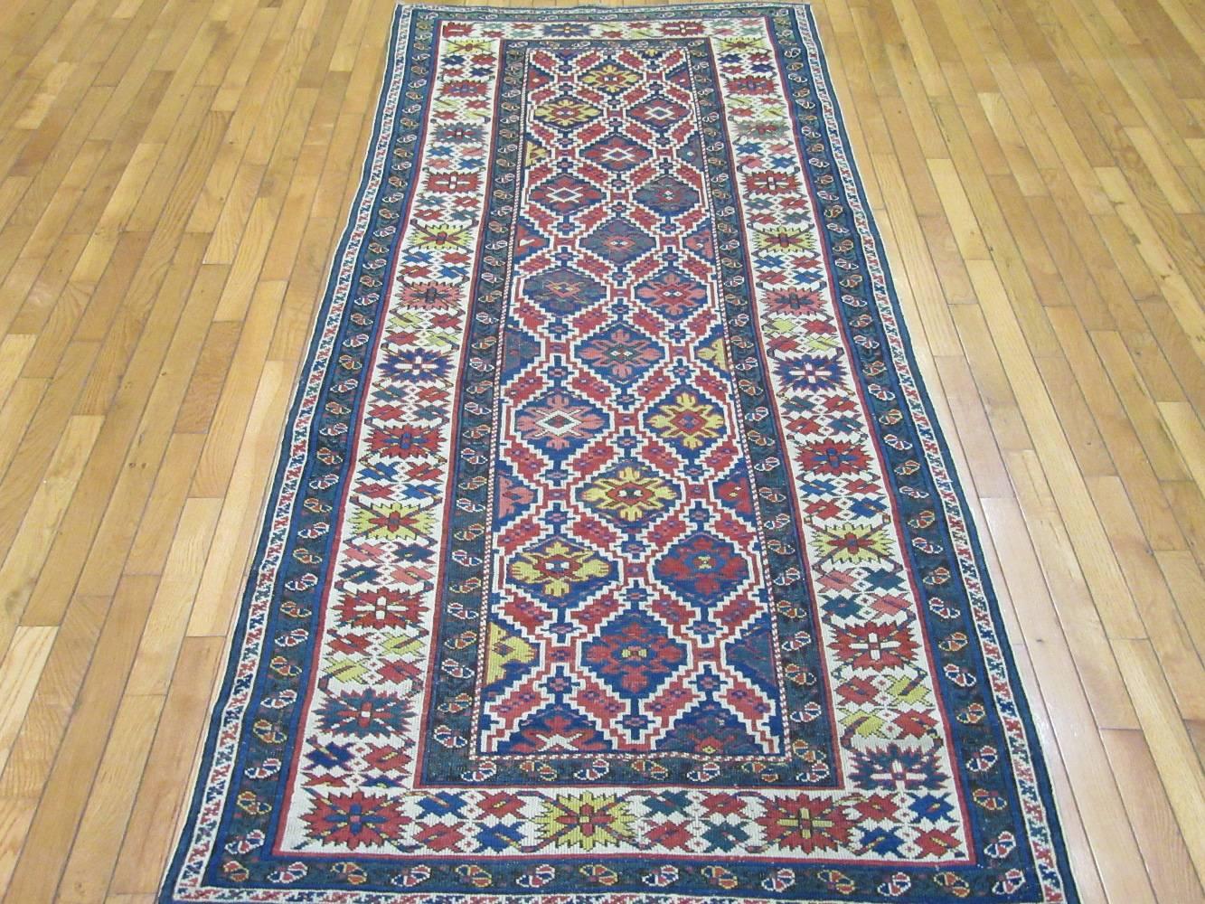 This is an antique hand-knotted short runner rug from the village of Shirvan in the Caucuses. Shirvans are among the better quality weave Caucasian rugs. It has a repetitive all over geometric pattern on a blue color field. The rug measures 3' 6'' x