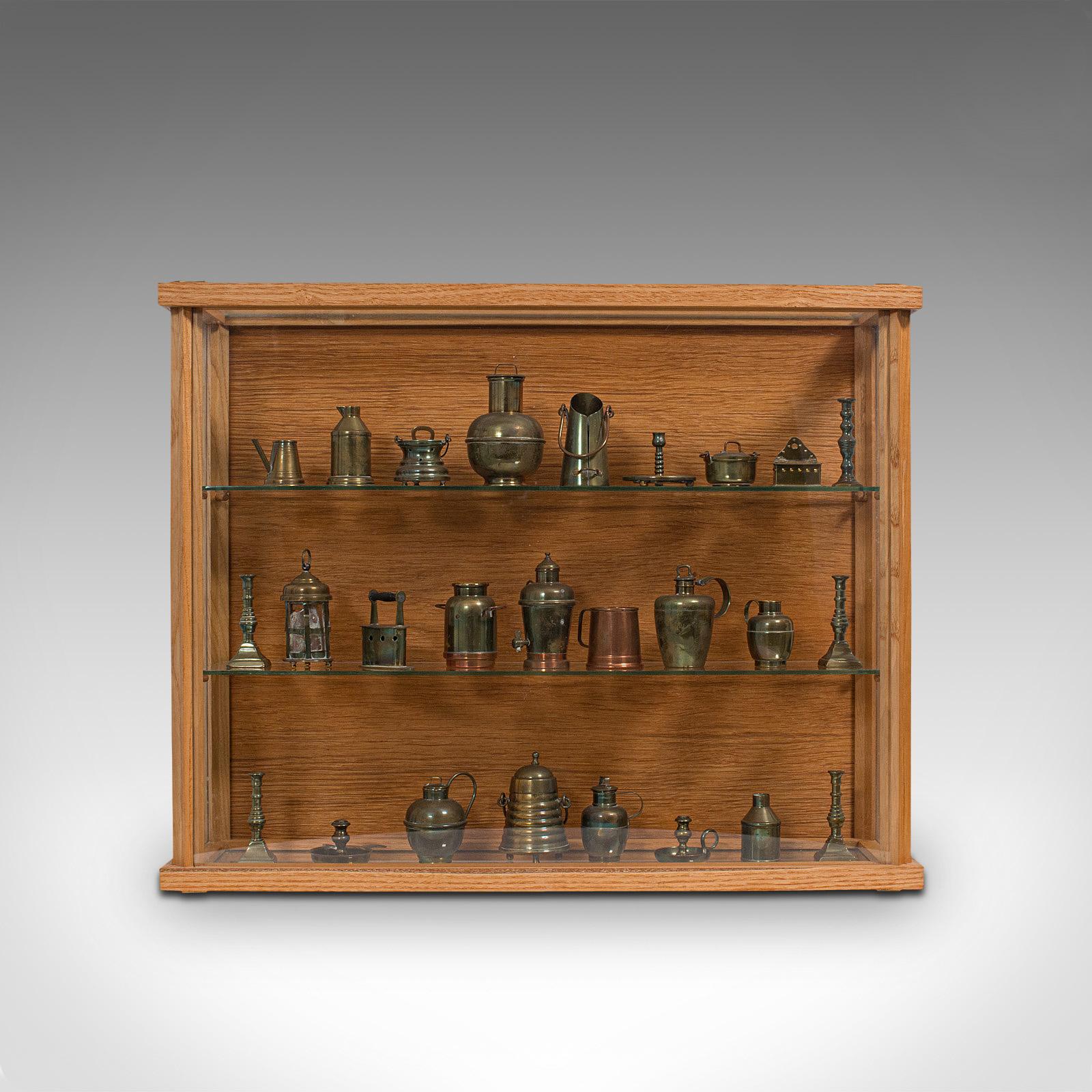This is a charming antique showcase collection of miniatures. An English, brass and copper set of Victorian collectibles with later display cabinet, dating to the late 19th century and later, circa 1900.

Diminutive but fascinating collection of