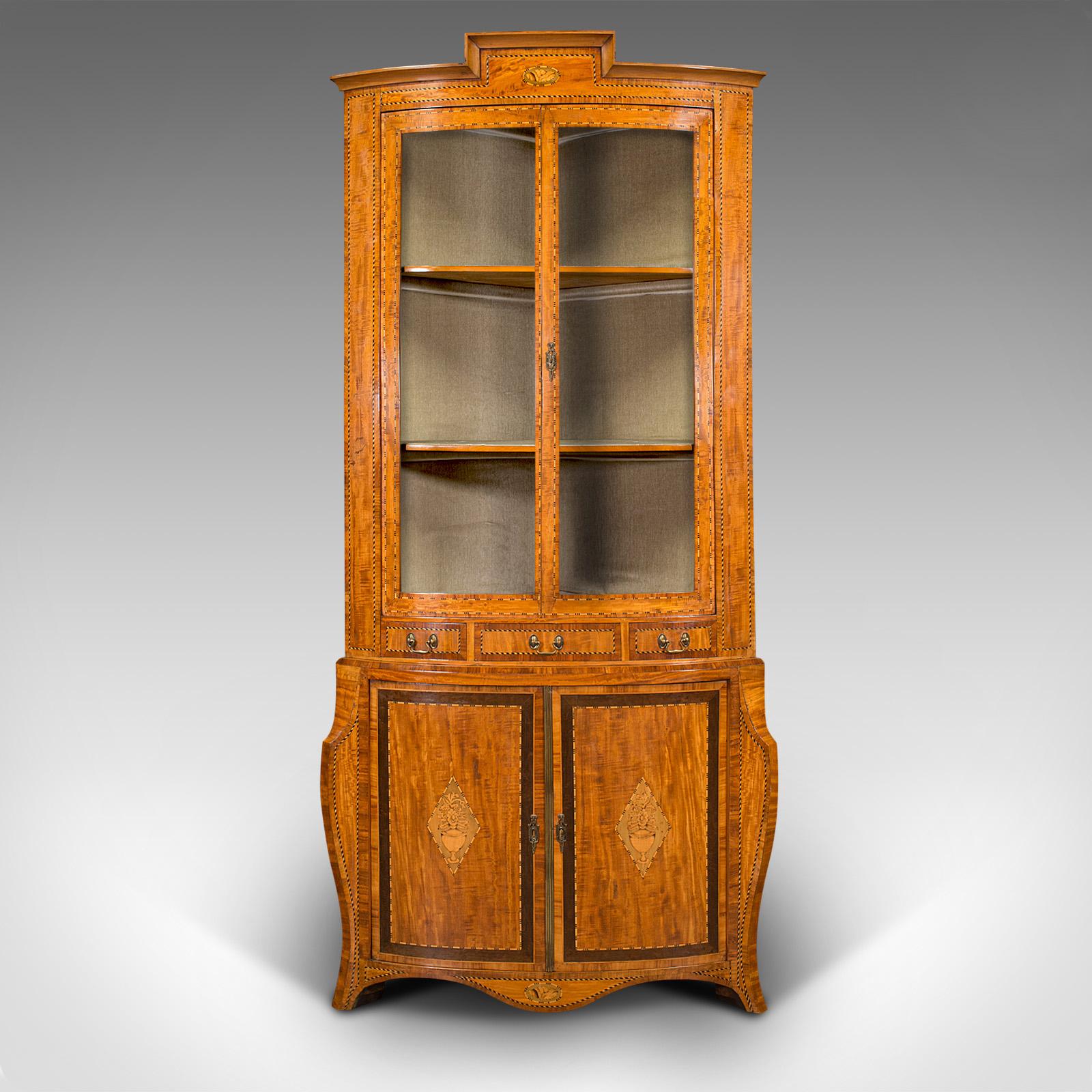 This is an antique showcase corner cabinet. A Dutch, satinwood bow-front display case, dating to the late Victorian period, circa 1880.

Of exemplary aesthetic appeal, with a striking finish and craftsmanship
Displays a desirable aged patina and