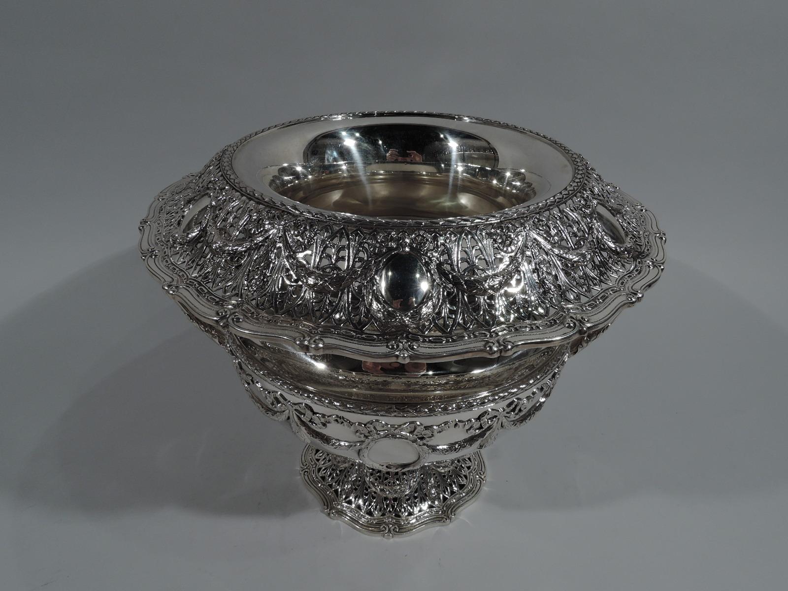 Edwardian Regency sterling silver wine cooler in Adam pattern. Made by Shreve & Co. in San Francisco, ca 1915. Bellied bowl, inset concave neck, turned-down and scrolled rim, and domed and scrolled foot. Leaf-capped and wrapped high-looping side