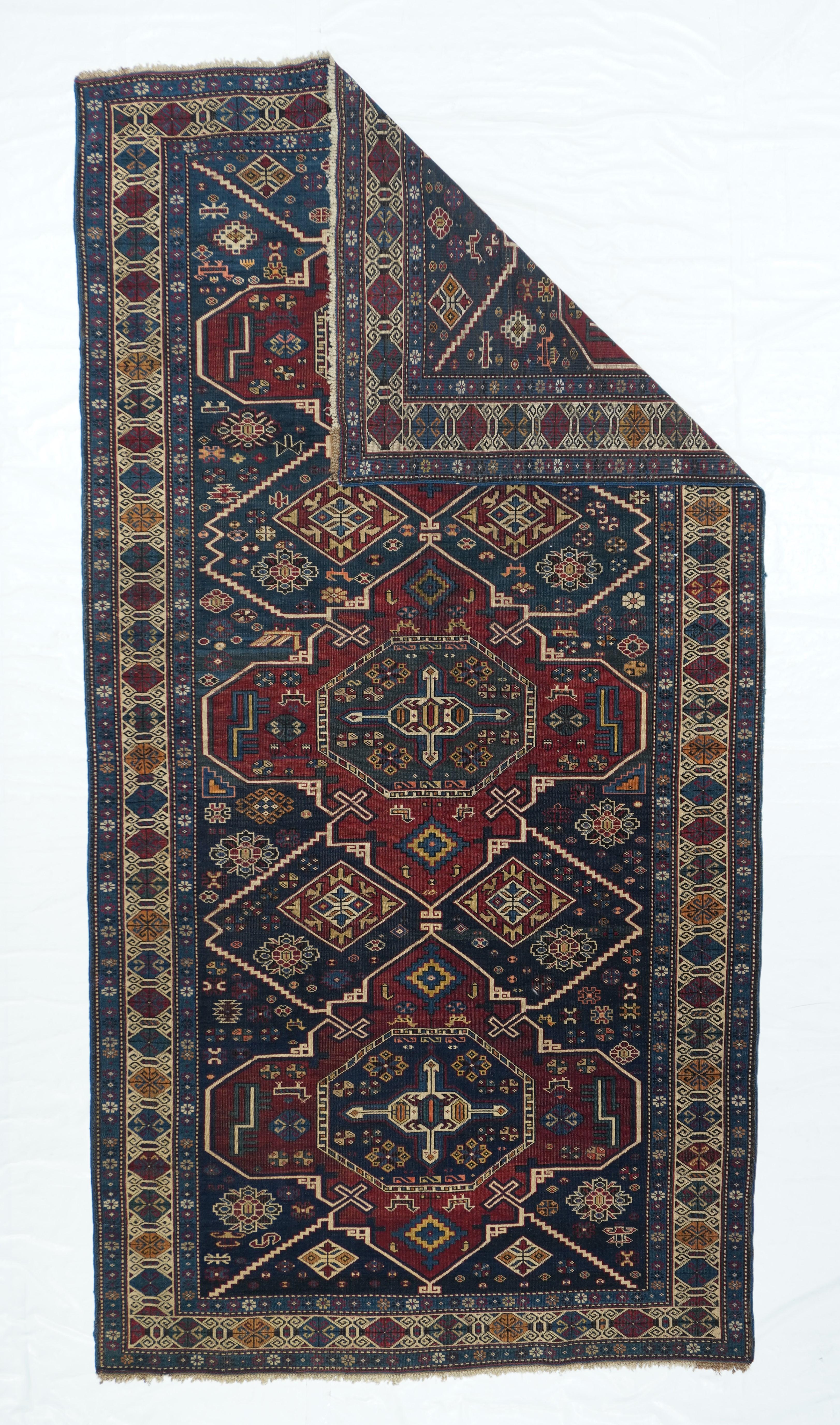 Antique Shrivan rug measures 4'4'' x 8'5''. With a beige wool warp more often attributed to Kuba in the eastern Caucasus, this village Kellegi (long rug) shows three red Soumak-style reticulated medallions linked by Navy reserves and stepped bent