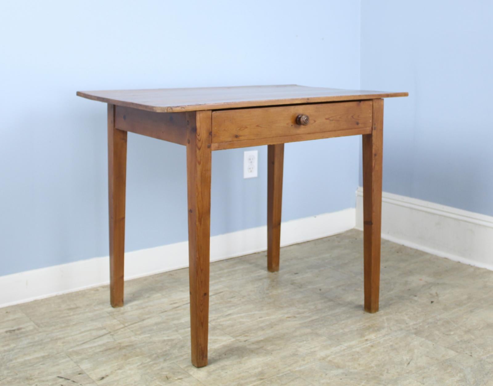 An elegant pine side table or small writing table with nice grain and patina. Classic tapered legs and a wide center drawer. Divided space in the drawer makes for good organizing. 24 inch apron height is good for knees.