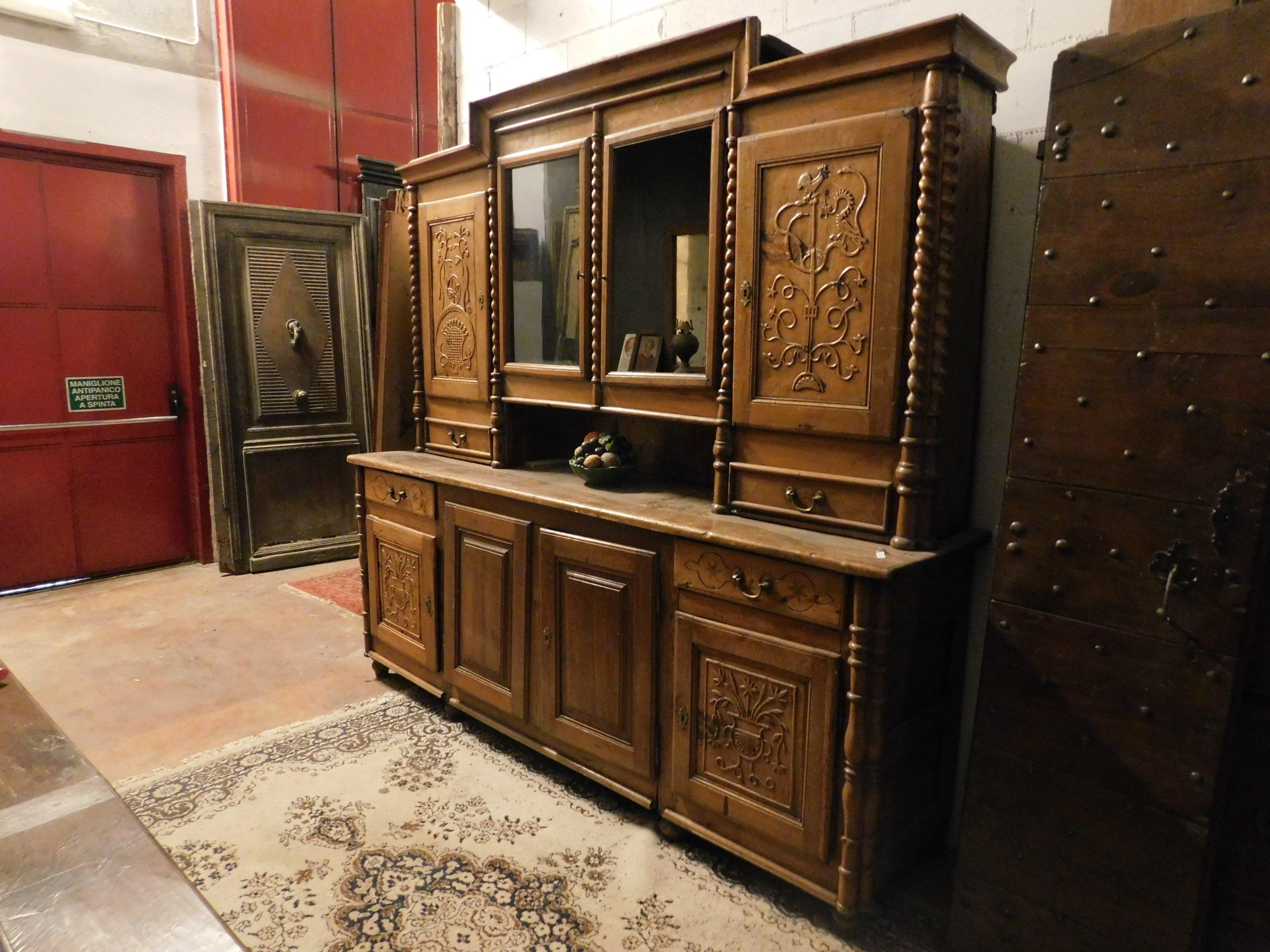 Antique cabinet with double body in larch wood, honey brown, hand carved with mountain theme (flowers and fauna, with edelweiss) from rustic cabin of 800 in Italy.
Composed of a low part with closed doors and a high part with open sections and