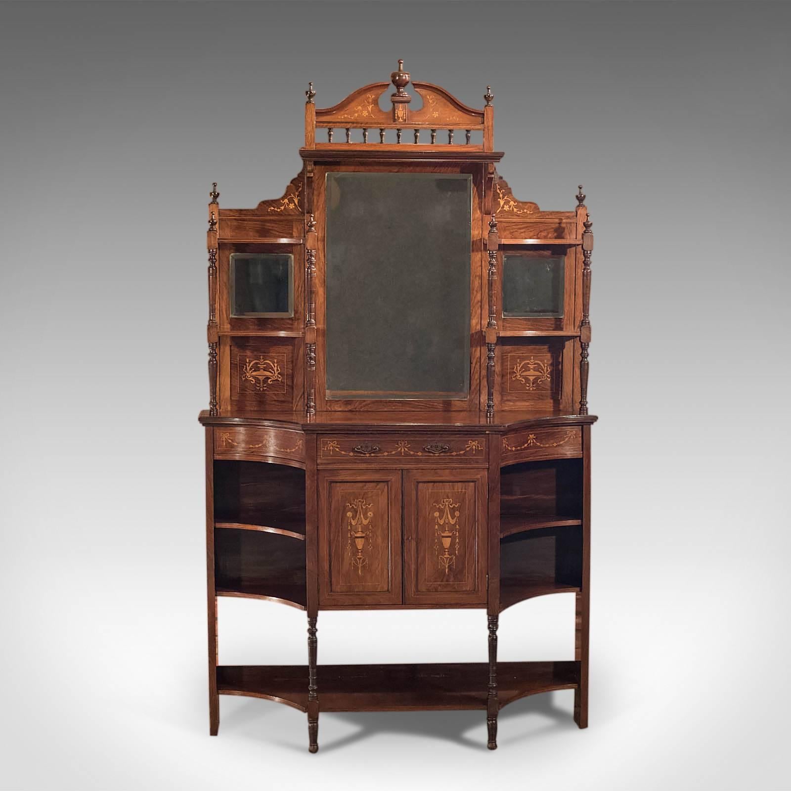This is an antique, Edwardian mirror back sideboard dating to the early 20th century, circa 1910.

Adorned with finals and classical motif in the boxwood inlay featuring urns, garlands and swags lend this piece the Greco overtones favored at the