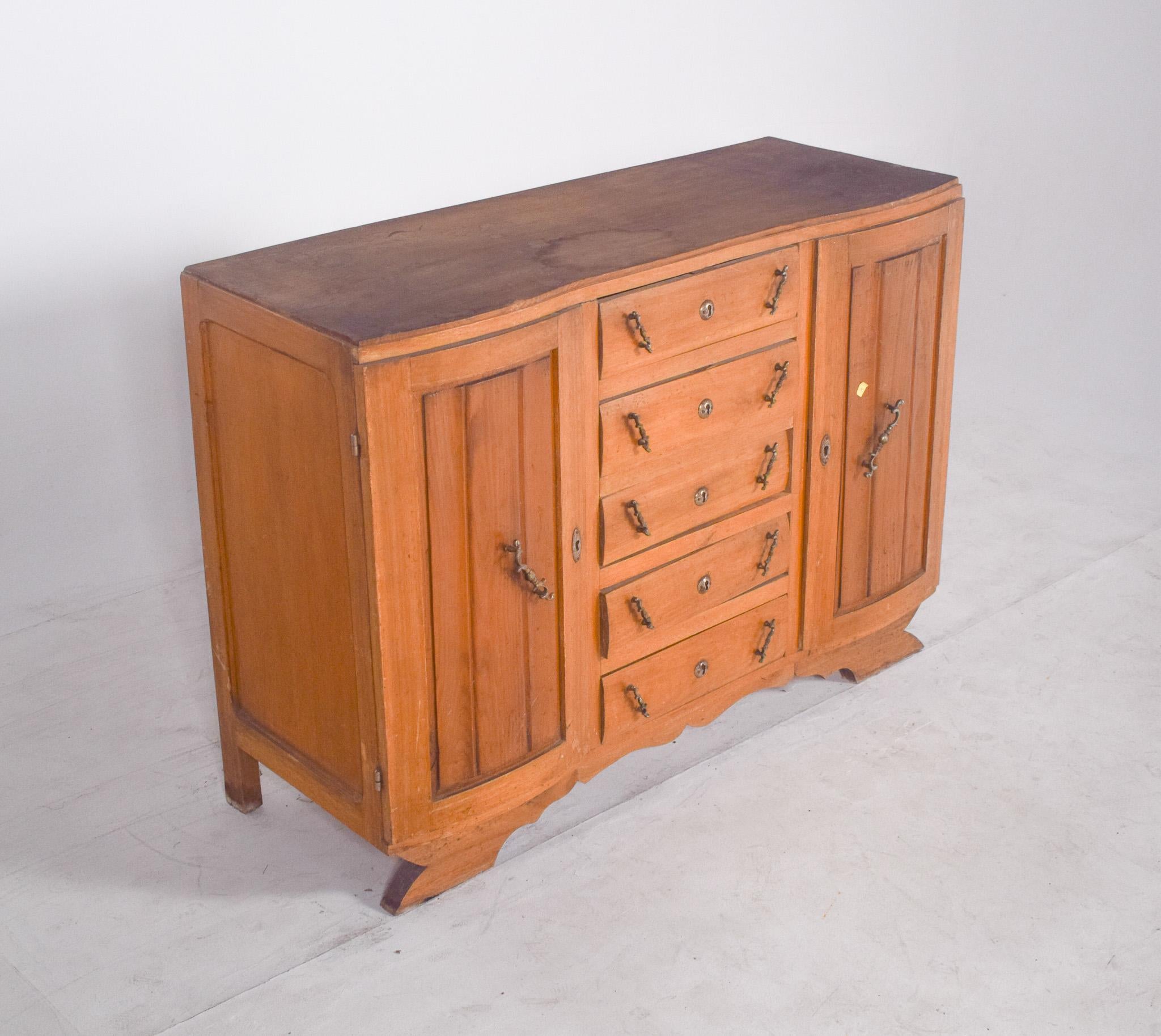 Sideboard with five drawers and two doors. Wood with a light finish and robust structure, comprising five central drawers and two side doors. The drawers have metal handles in pairs, arranged diagonally, creating a distinctive and functional visual