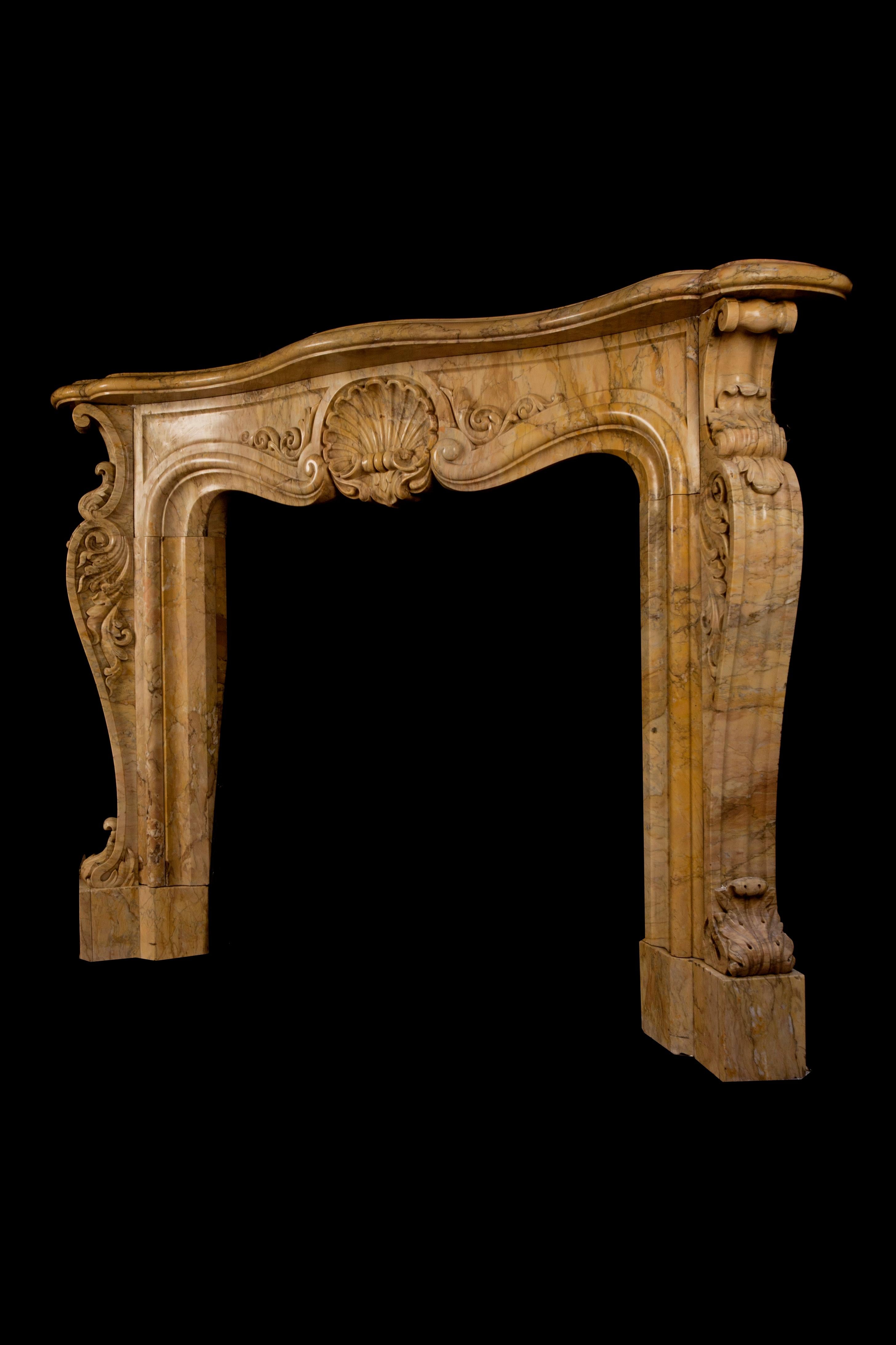 A most stunning Sienna marble chimneypiece in the Rococo Revival style.

A large shell cartouche is flanked by scrolled foliage on raised and fielded panels. The angled cabriole jambs are decorated with acanthus leaves on the front and sides. The