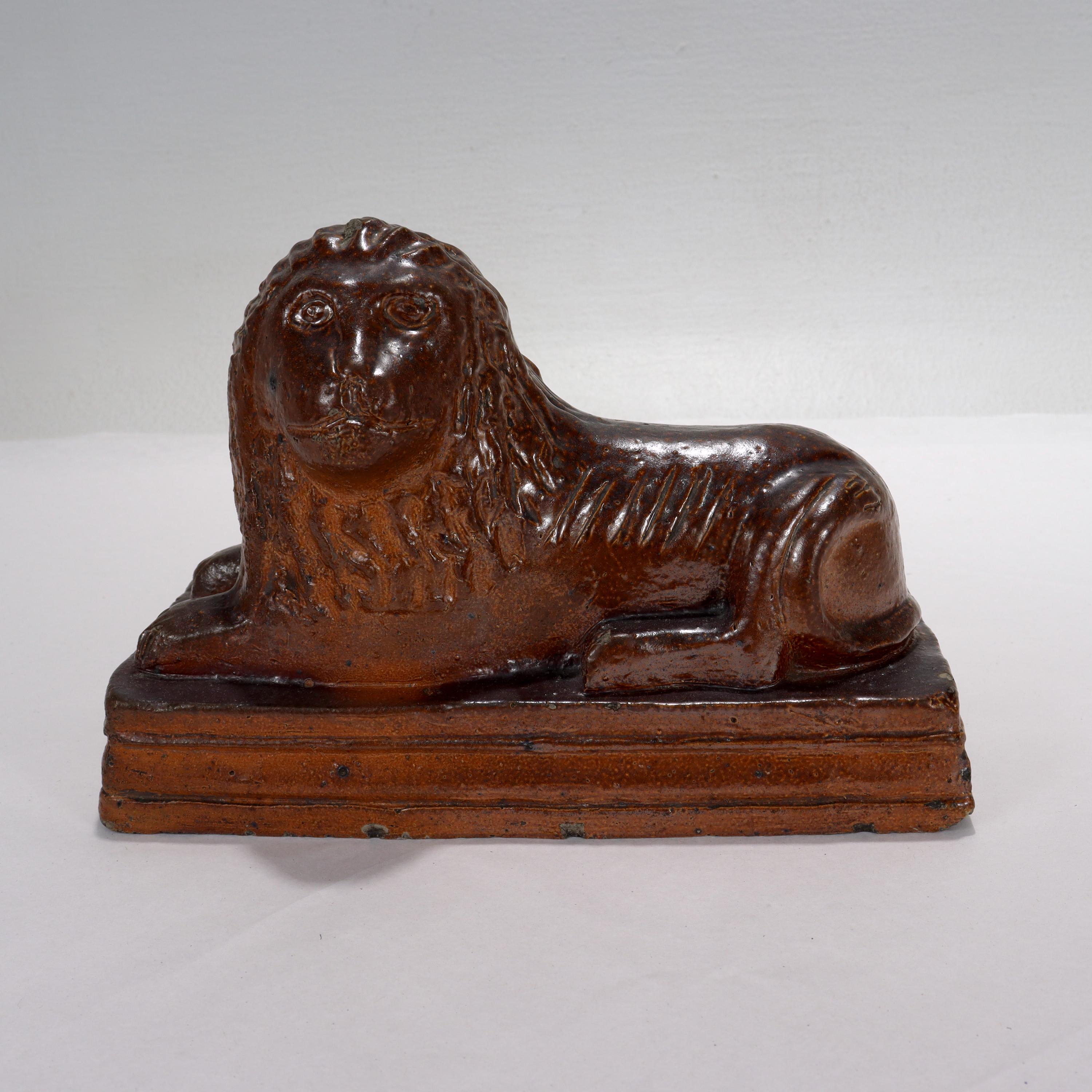 A fine antique signed Folk Art lion figurine.

In the form of a recumbent lion. 

Signed to the underside. The signature appears to read: 'J Silverthorn'

Made out of a reddish-brown redware or stoneware sewer tile pottery.

Simply a great