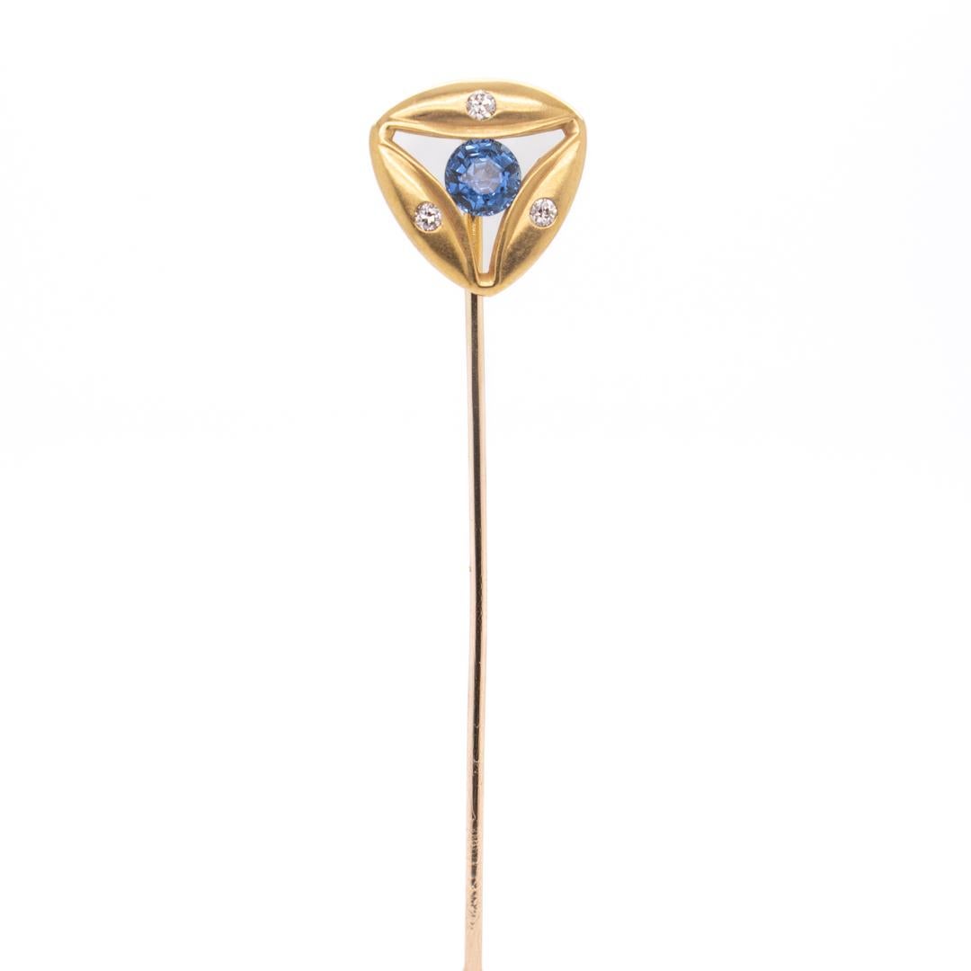 A fine signed Art Deco period stick pin.

By the Brassler Co. Inc.

In 14k yellow gold.

With a tension-set round cut central lab-created sapphire surrounded by 3 white diamonds in a slightly convex brush-finished geometric Art Deco setting.

Signed
