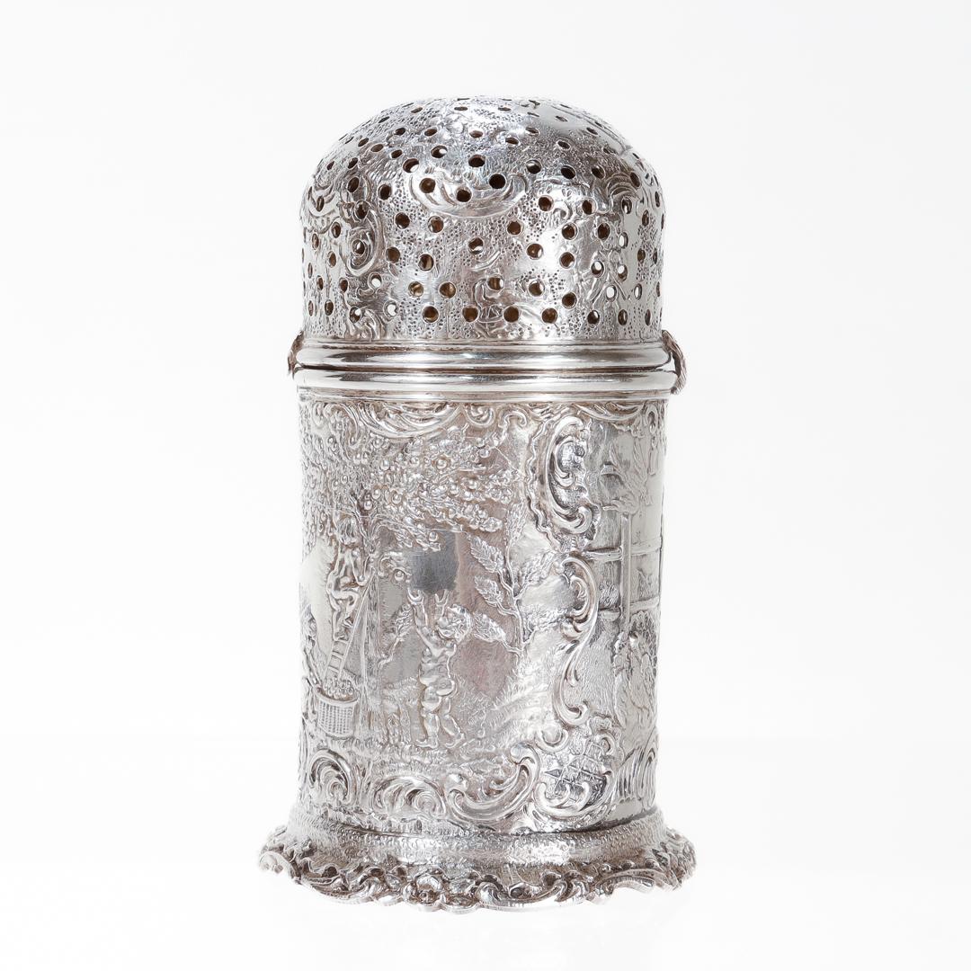 A fine 800 silver muffineer.

By Storck & Sinsheimer.

Of a bullet form with rocaille embellished foot and a repousse decorated body and cover.

The repousse decoration includes depictions of cherubs picking apples, a barnyard scene, cherubs