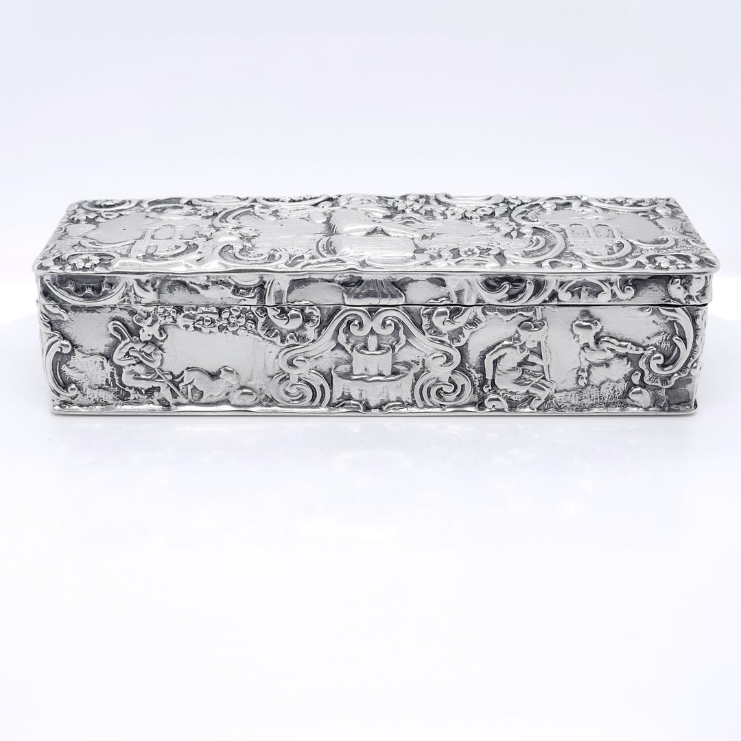A fine antique, small-scale rectangular dresser box.

In 800 silver.

By the German silversmiths Storck & Sinsheimer of Hanau, Germany.

With a conforming, hinged lid and repoussé decoration throughout.

Marked with psuedo-Hanau hallmarks for Storck