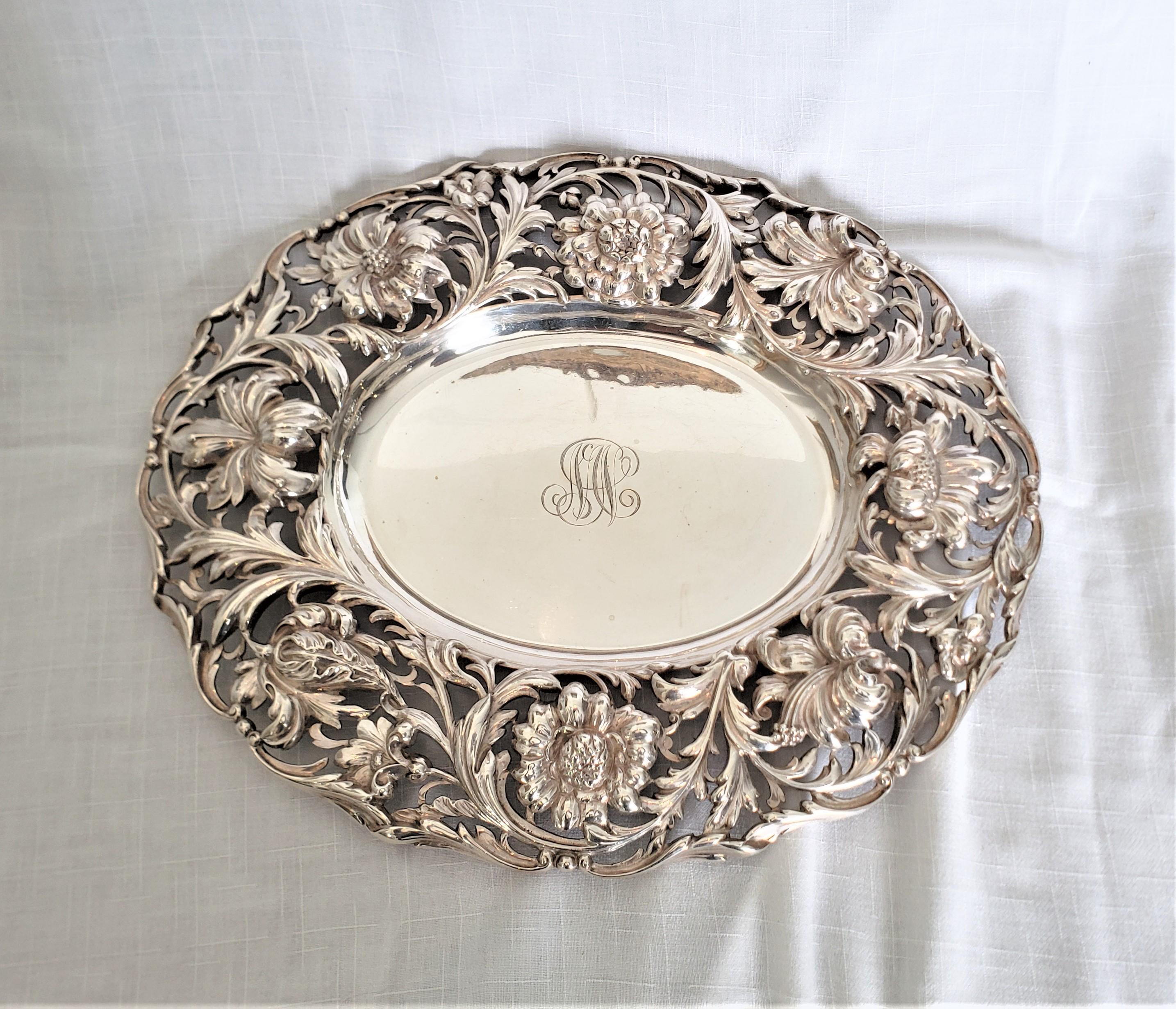 This antique sterling silver serving dish or tray was made by the renowned Tiffany and Co. of the United States in approximately 1860 in the period Victorian style. This oval sterling silver tray is monogrammed and features a large rim exquisitely