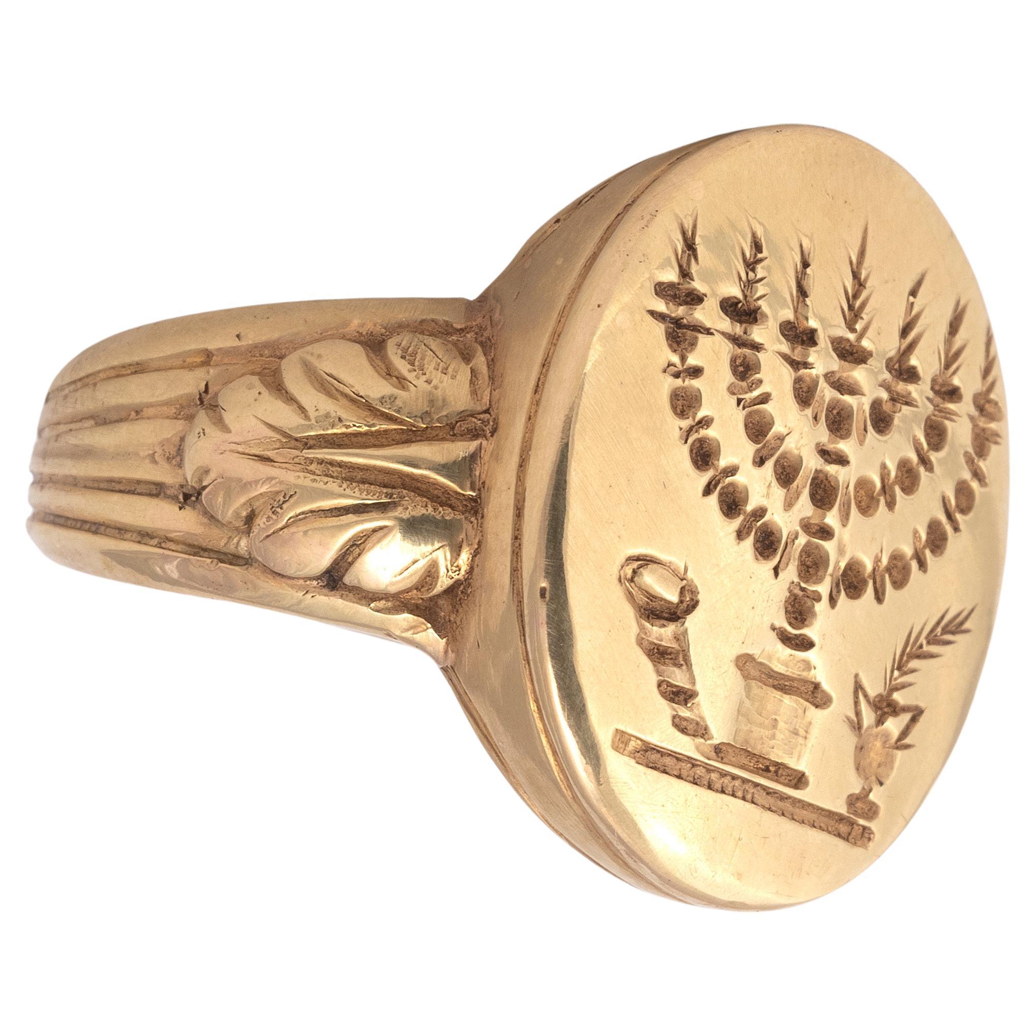 Antique signet jewish ring depicting a large candelabra or Menorah which has lit candles or tapers.Flanking the candlestick are a ram's horn or shofar and a vase with a palm frond, both symbols frequently encountered on representations of the