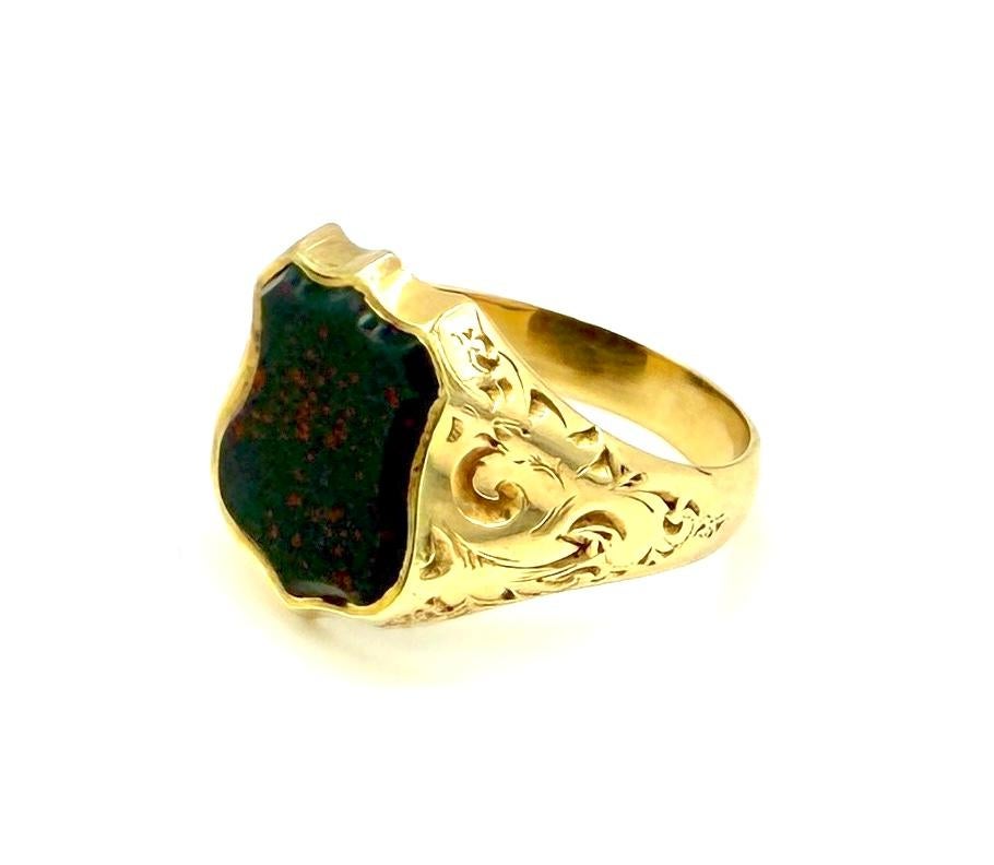 Cette chevalière ancienne a été créée dans le dernier quart du XIXe siècle. Il est réalisé en or jaune 14 carats. L'héliotrope ou pierre de sang est taillée en forme de bouclier et sertie dans une monture ouverte. Les épaules de l'anneau suivent