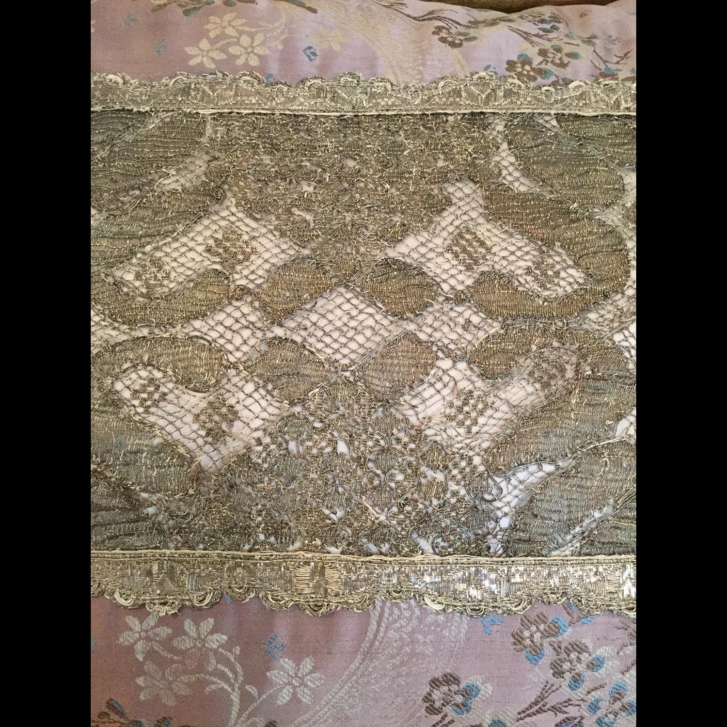 18th century, Italian purple silk lampas with ivory and light blue flowers frames a central panel of rare 18th century, French needle lace bordered by scalloped 18th century Italian silver trim. Italian ivory silk completes the back. Down filled.