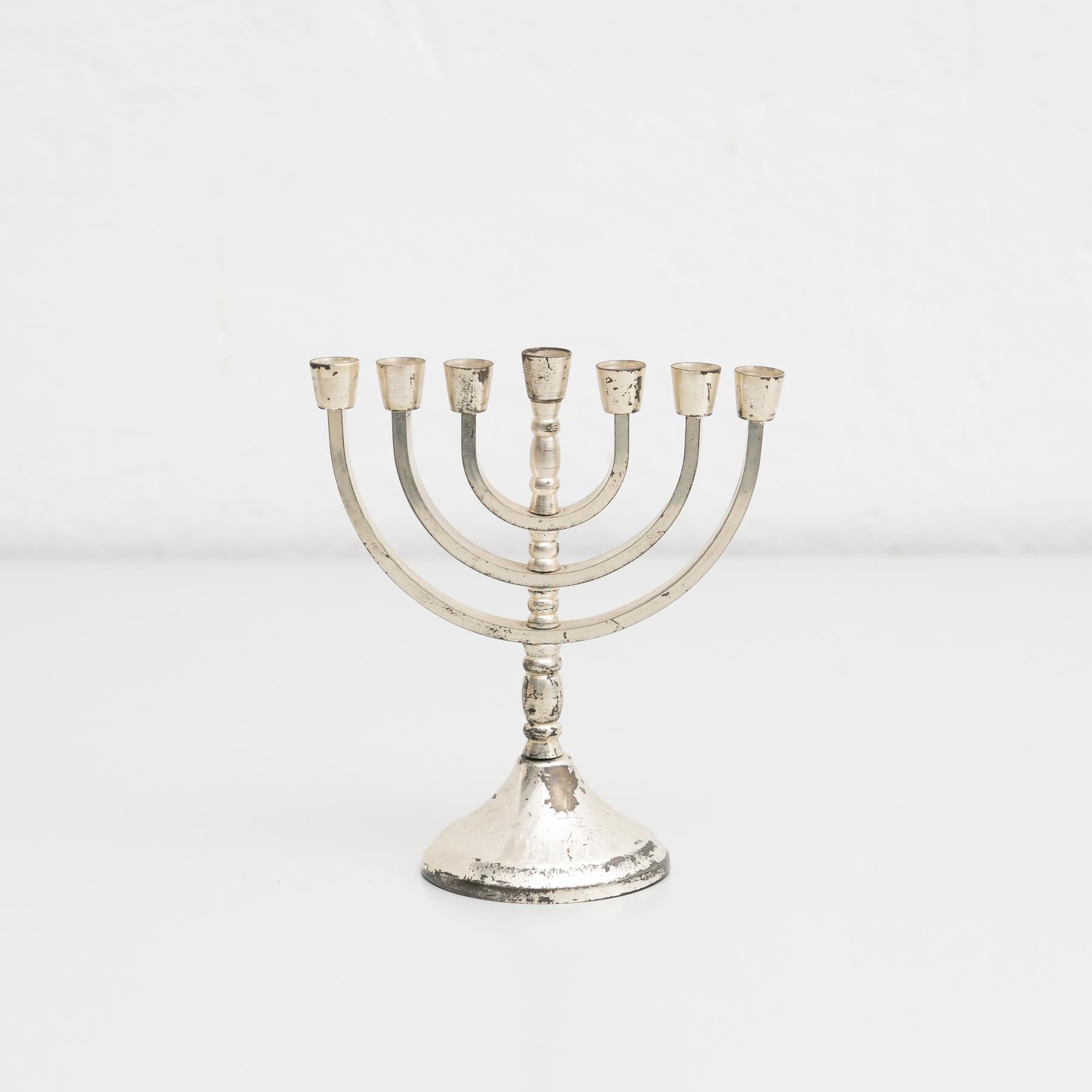 Antique traditional menorah silver candle holder with seven branches. It is used to celebrate, remember, and honor the historical miracle of Hanukkah.

By unknown manufacturer in Jerusalem, circa 1950.

In original condition, with minor wear