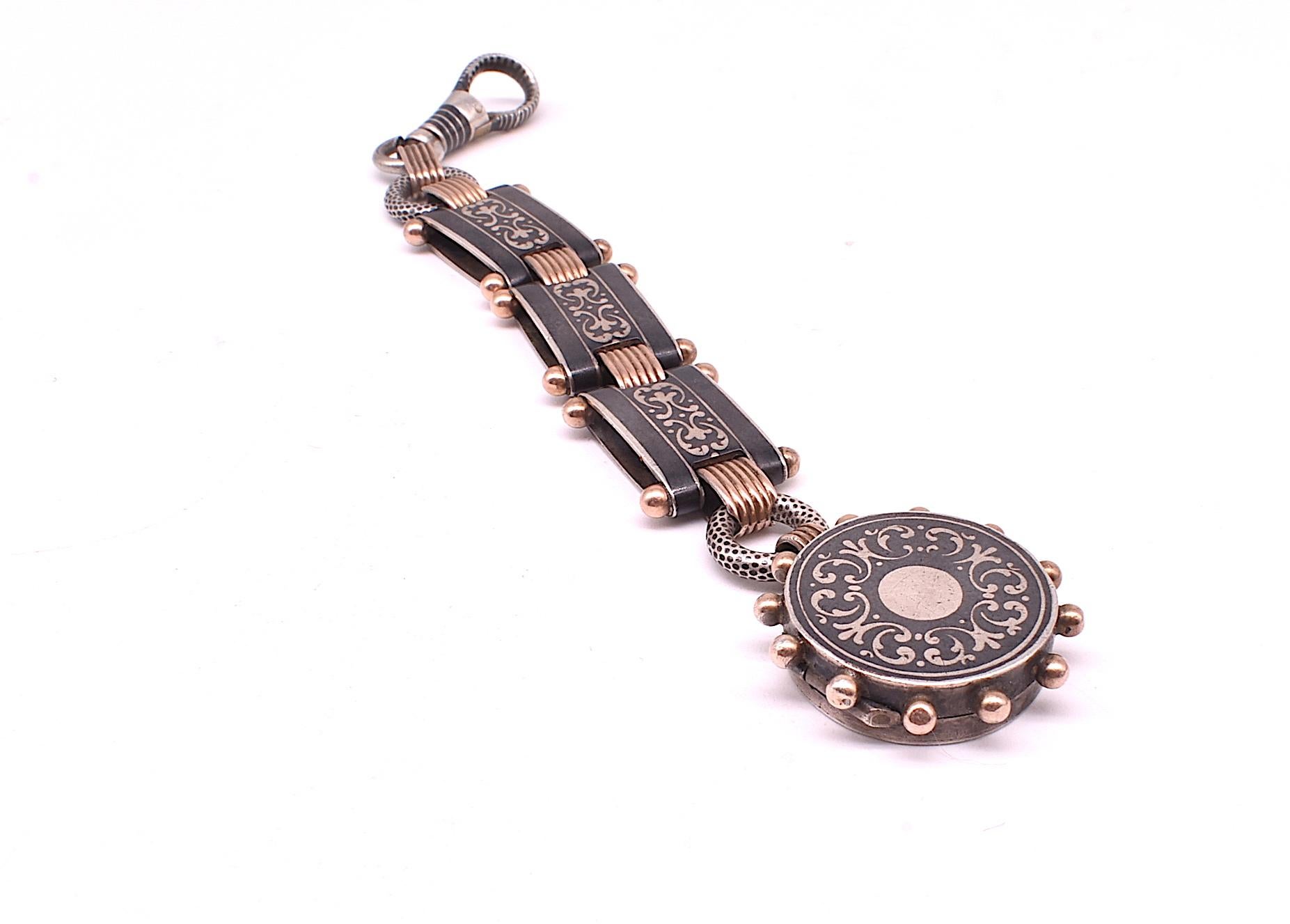 The rare fob pendant that is 3 pieces in 1; it includes a beautiful large niello dog clip which attaches to 3 niello links which further attaches to a 2 compartment round locket, .75 inches in diameter..  Long and elegant, the dog clip allows you to