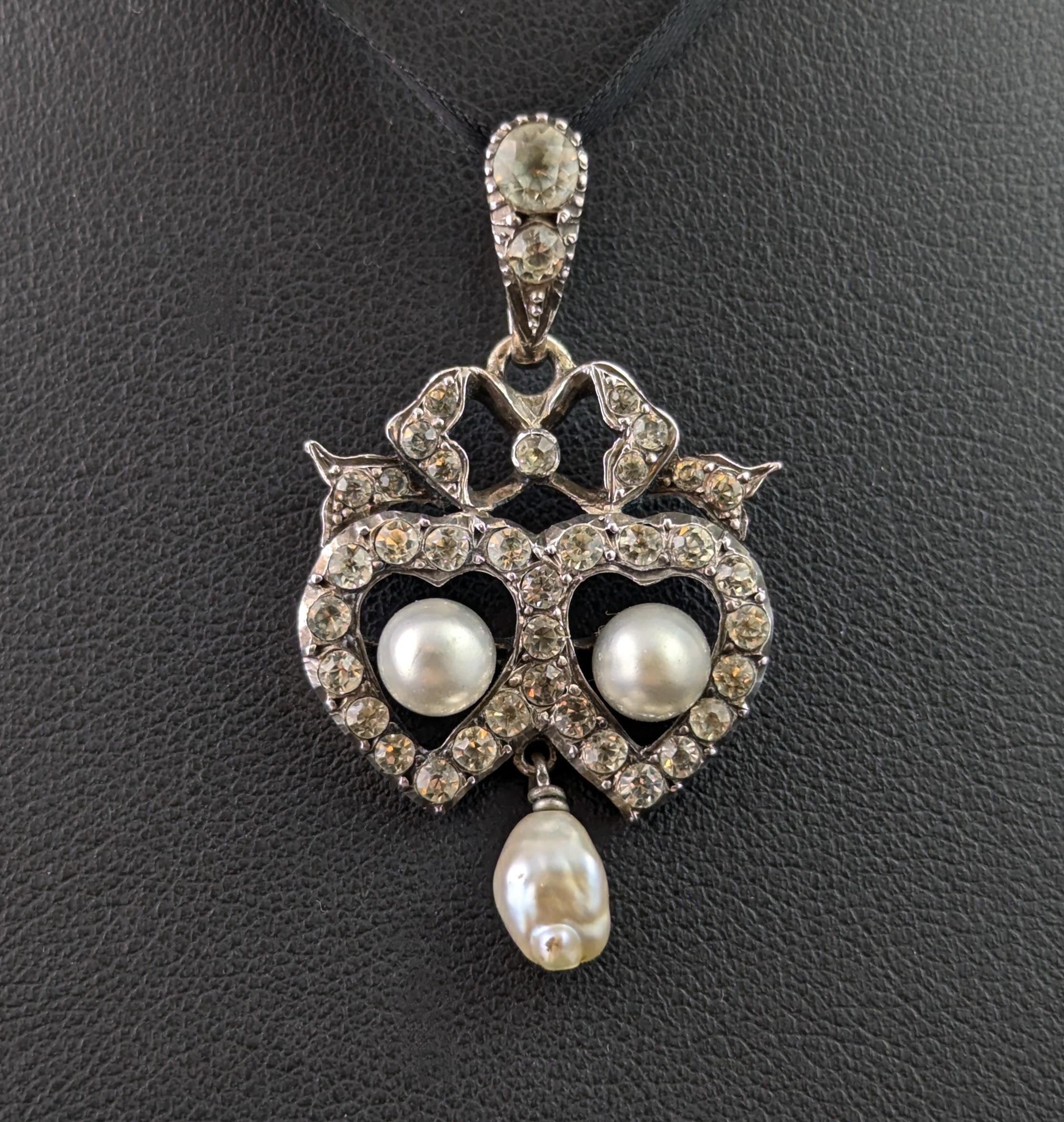 Magnifique pendentif double cœur et nœud d'époque édouardienne.

Comme c'est beau ! Pas un mais deux jolis cœurs d'amour entrelacés avec un nœud au sommet.

Le pendentif est fabriqué en argent 900 et orné de pierres en pâte claire. Deux fausses