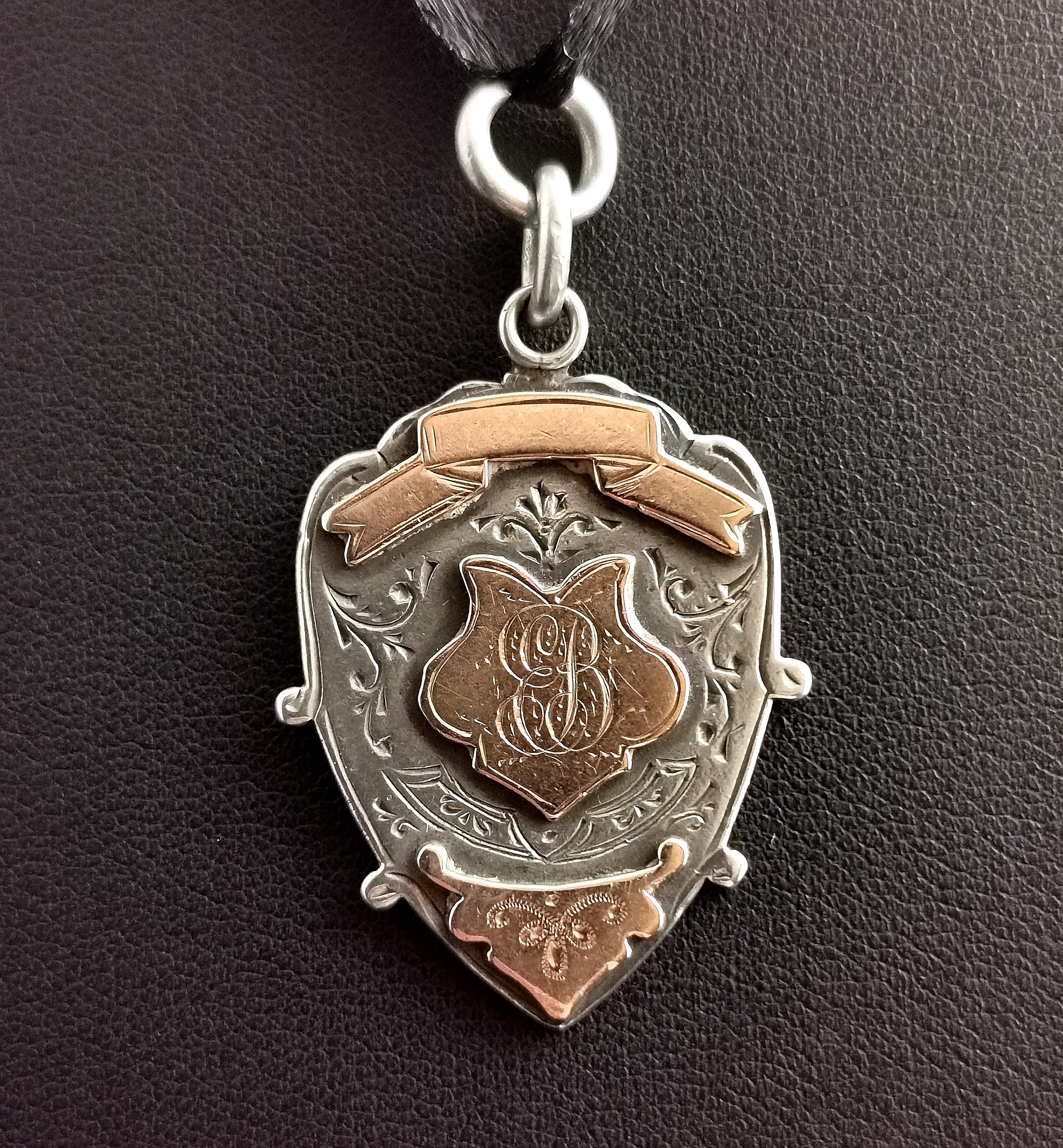 A handsome antique, Edwardian sterling silver and Rose gold fob.

It is a shield shaped fob with a 9k Rose gold applied raised cartouche to the centre and scroll to the top, the centre is monogrammed with the initials EB.

The lower part also has an
