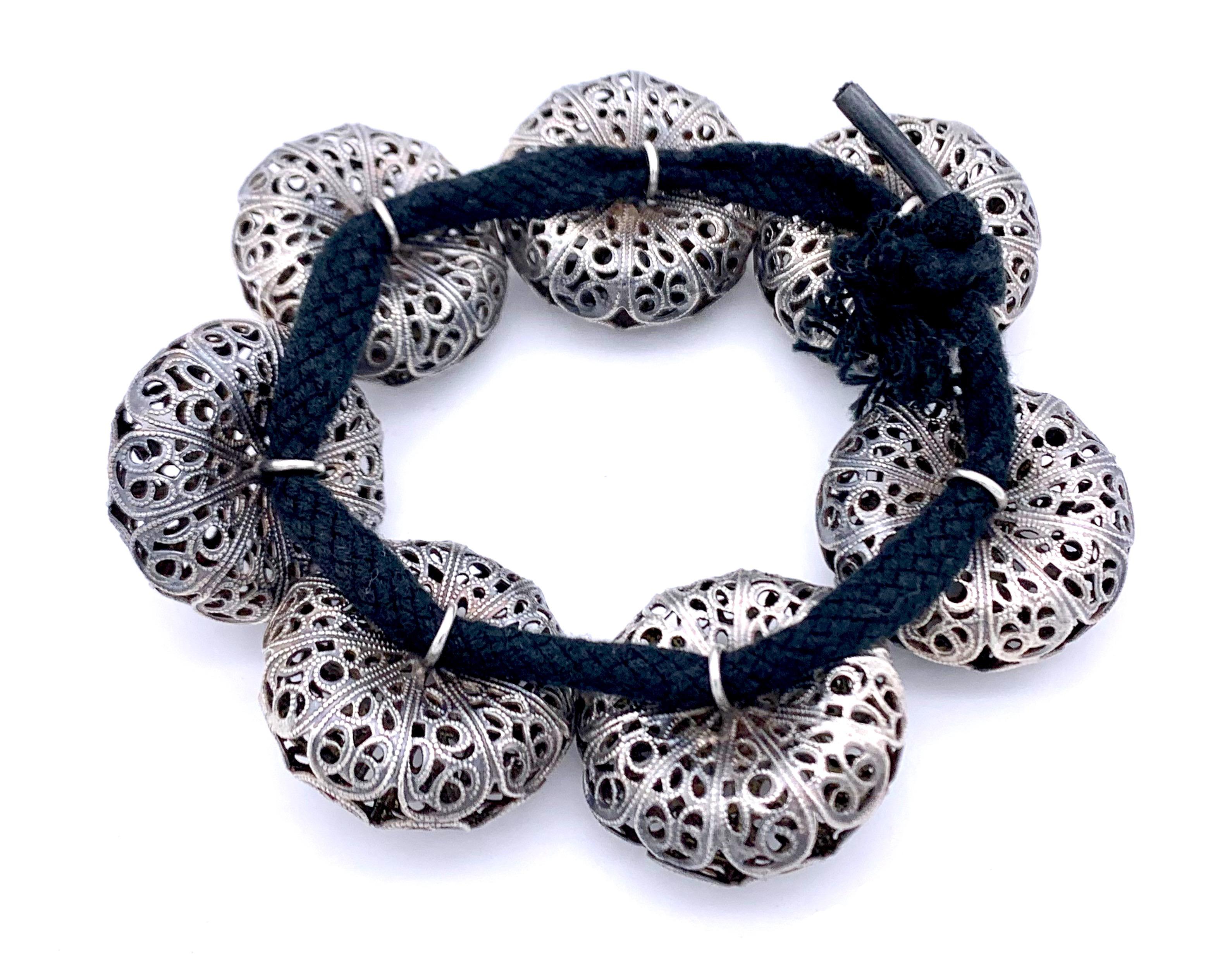 These wonderful silver buttons are strung onto a  black cotton string to make up a bracelet.
The buttons were hand crafted in the second quarter of the 19th century. Fine silver wire work is decorated with silver flowers and applied lozenge shapes. 
