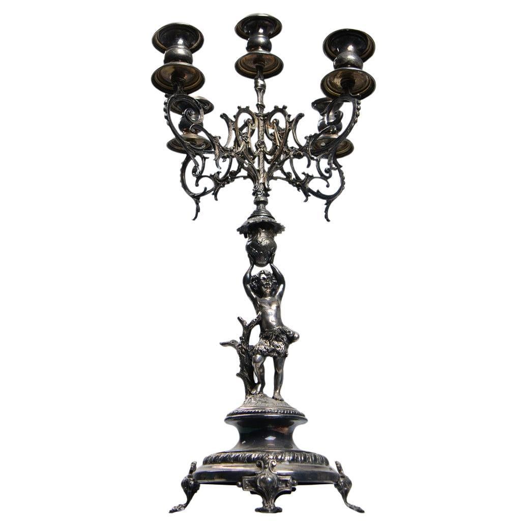 Bougeoir ancien de style rococo en métal argenté avec sculpture de figurine pressée, coulée et ciselée. Pieds circulaires et incurvés avec charnières. Testé avec le scratch test, hauteur environ 52 cm, diamètre 20 cm. Des courbes en C en relief, des