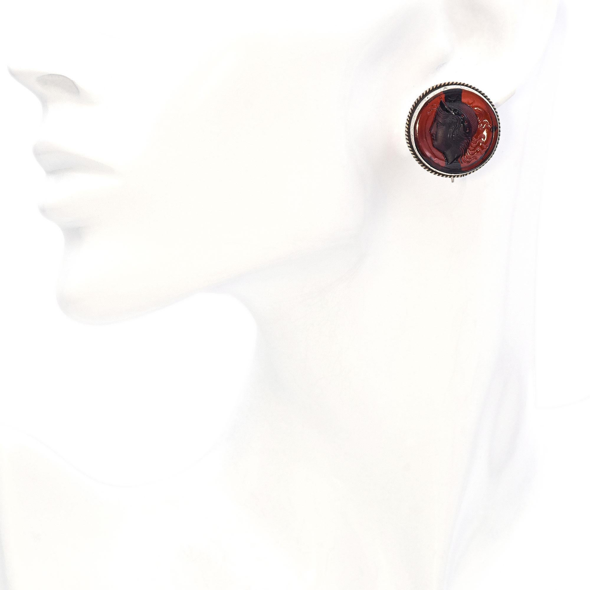 These stunning antique silver clip-on earrings feature intricately carved Carnelian intaglios, depicting a regal warrior in the style of Ancient Roman craftsmanship. The intaglio technique, historically used for signet rings and seals, gives these