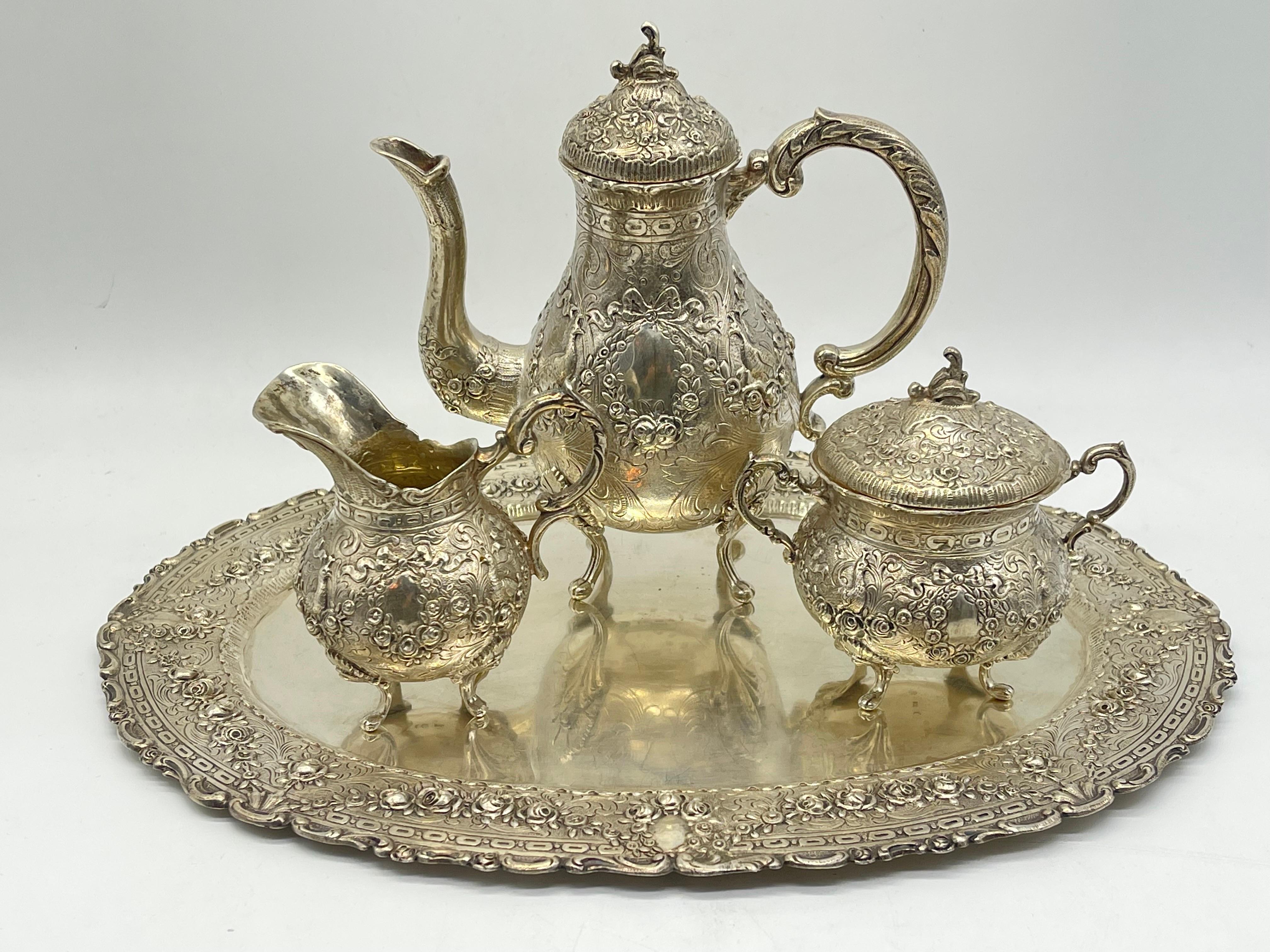 Centro de mesa de plata con pastilla 800 Alemania Adorno Rosas Cisne 

4 piezas 
cafetera (altura 18 cm)
caja de azúcar (altura 10 cm)
jarra de leche (altura: 9 cm)
tableta (32 cm x 24 cm)

Media luna y corona

Peso: 1233 gramos

El estado puede