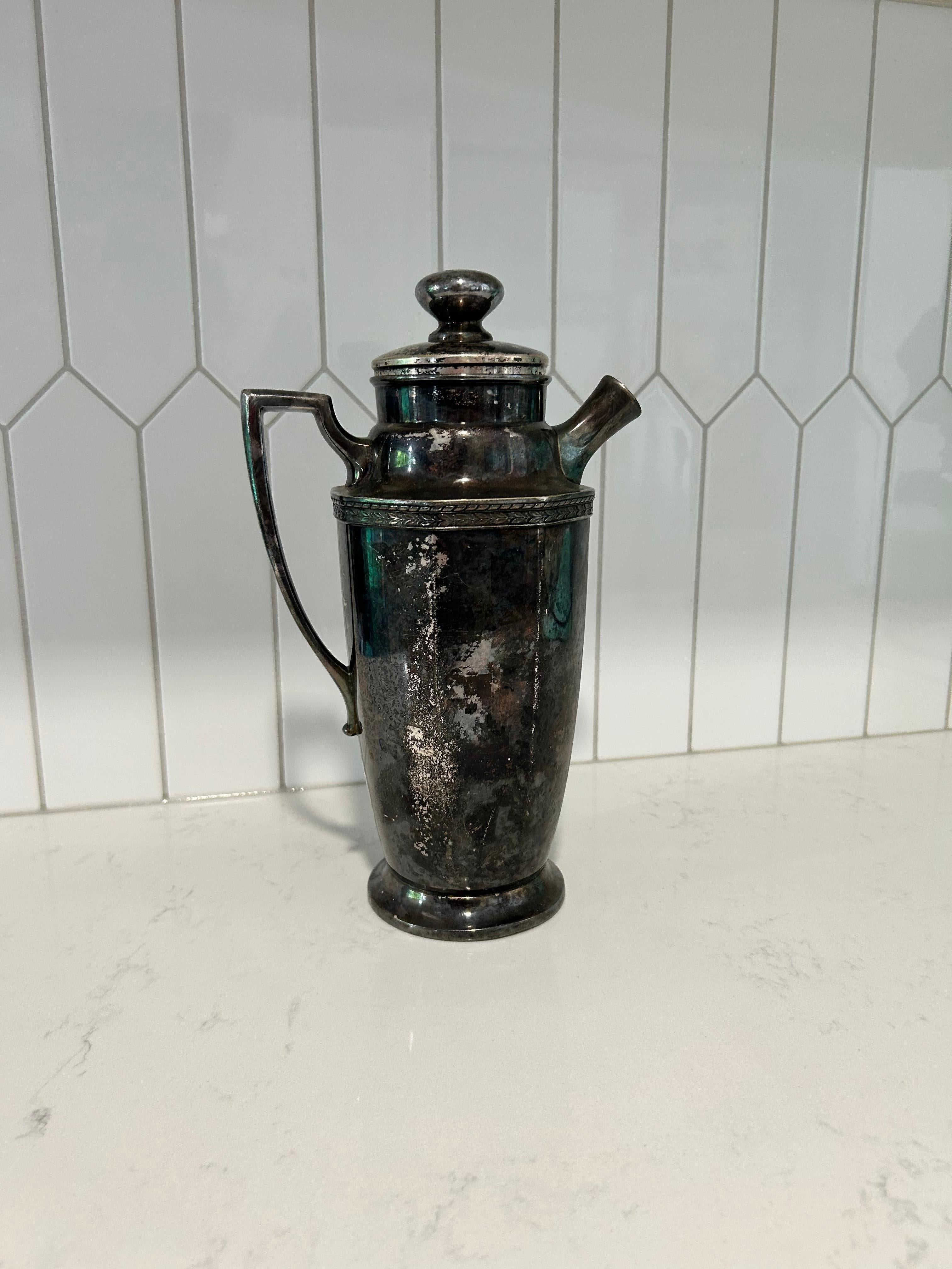 Peppen Sie Ihre Bar auf mit diesem antiksilbernen Cocktail-Shaker von Homan Plate, hergestellt in den USA.  Sein klassisches Design zeichnet sich durch einen sicheren Deckel, einen glatten Ausguss und einen eleganten Griff aus.  Die gealterte Patina