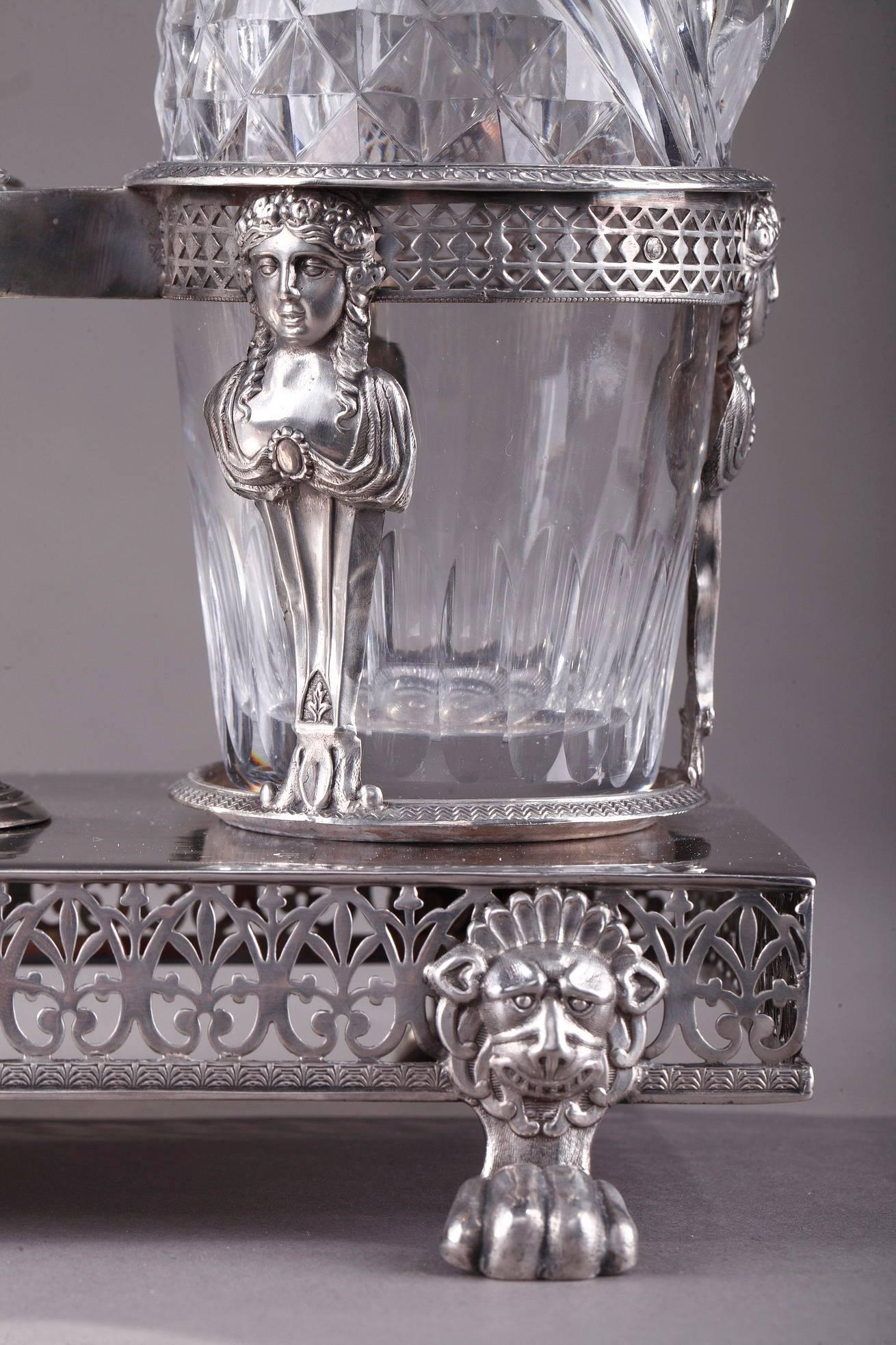 French antique three-piece cruet service in Directoire/Consulate style. The set consists of two cut crystal bottles: two carafes for oil and vinegar, held in place on a rectangular silver platter decorated with pierced foliage, resting on four lion