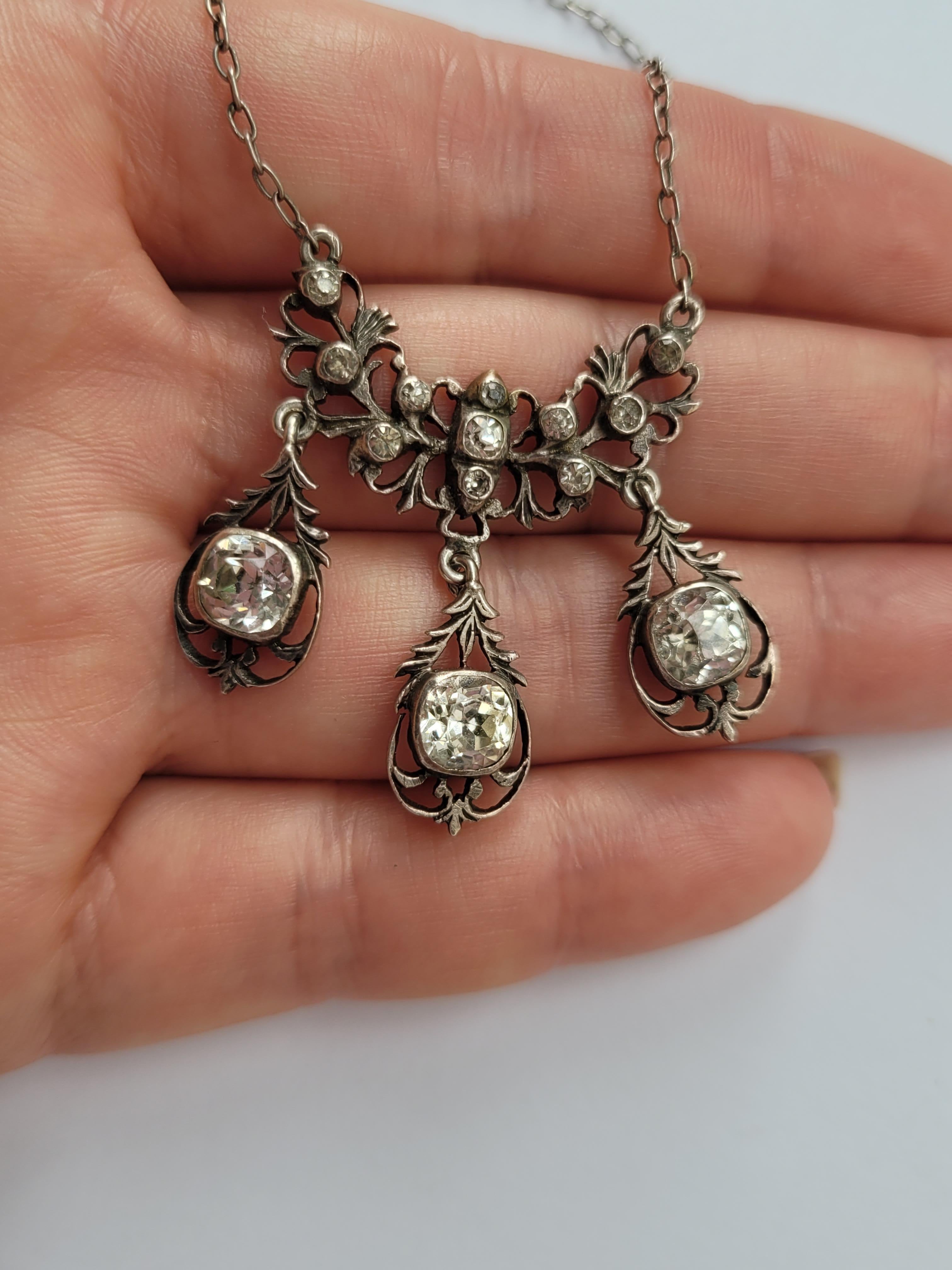 This solid silver and round and cushion cut paste drop necklace is a stunning piece from the late 1800s or early 1900s. Crafted in Georgian style, it comes with an original silver chain and stones in a closed back setting. 

Drop of the front