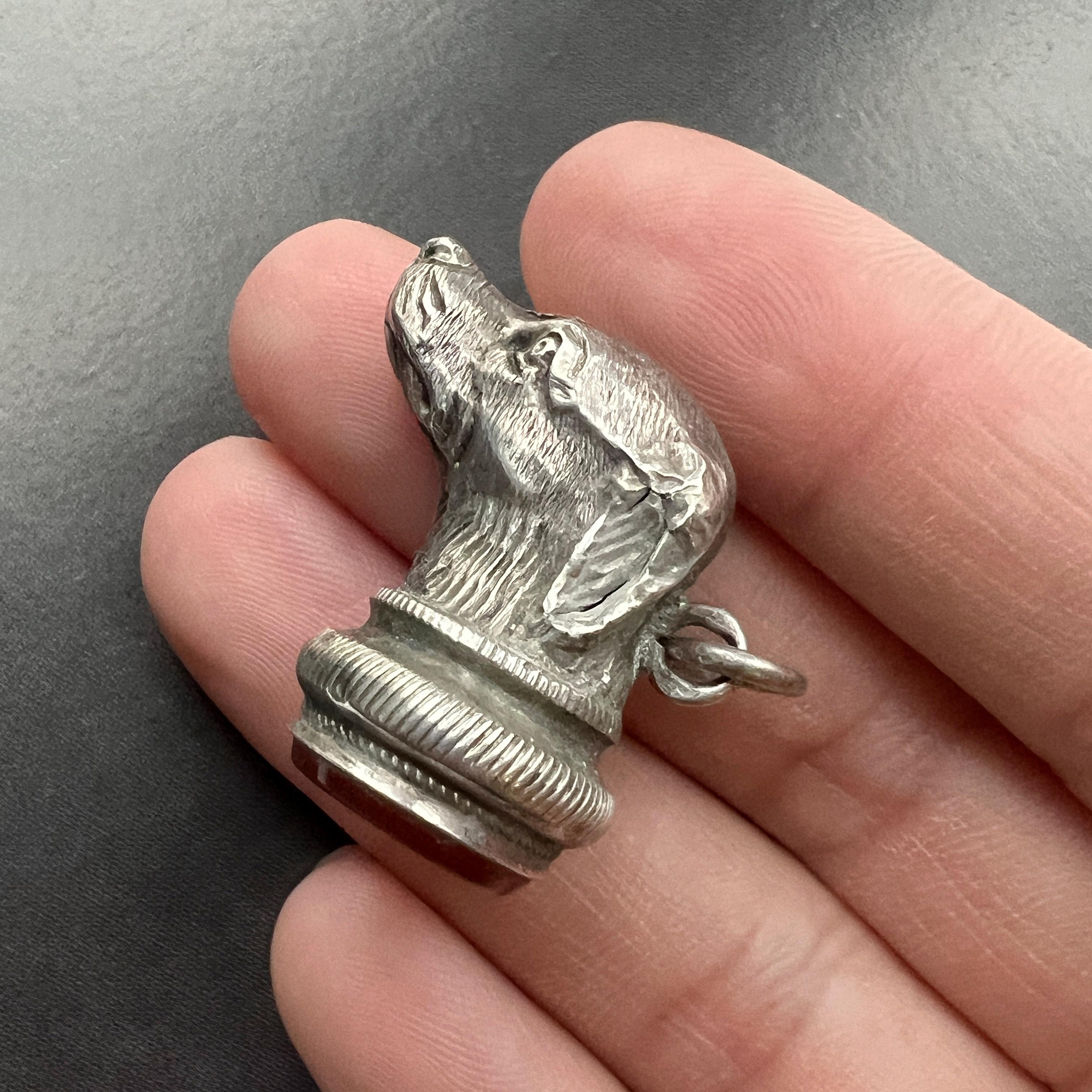 For sale an exquisite Victorian era silver dog fob pendant. It features a meticulously crafted 3D miniature of a dog, showcasing intricate details of its fur, expertly brought to life through skillful artisanship. The double-sided engraving allows