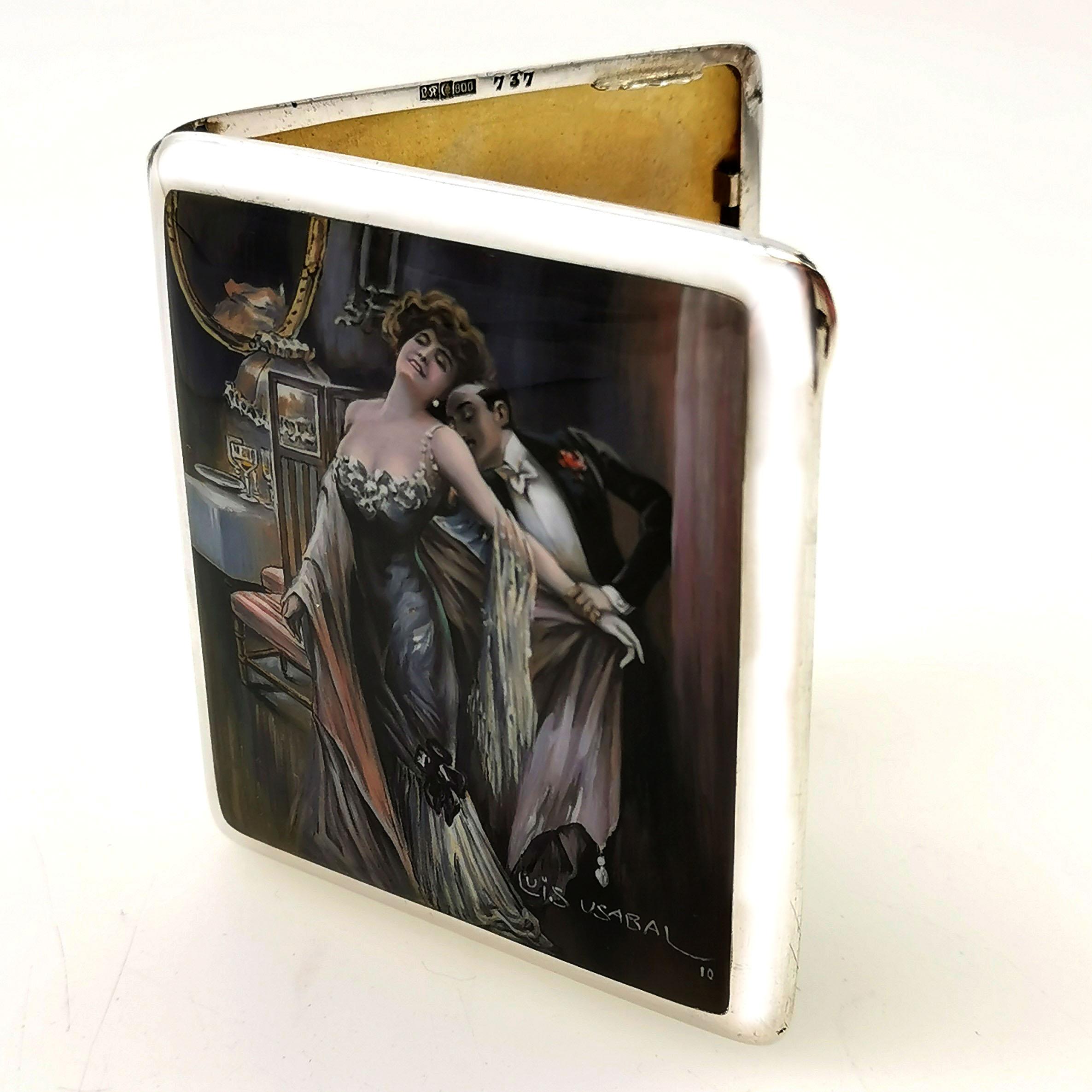 A magnificent Antique solid Silver Cigarette Case with a beautiful Enamelled cover signed by Luis Usabal. The image on the cover of the Case shows a couple in an embrace wearing evening wear in a detailed dining room setting. This image is created