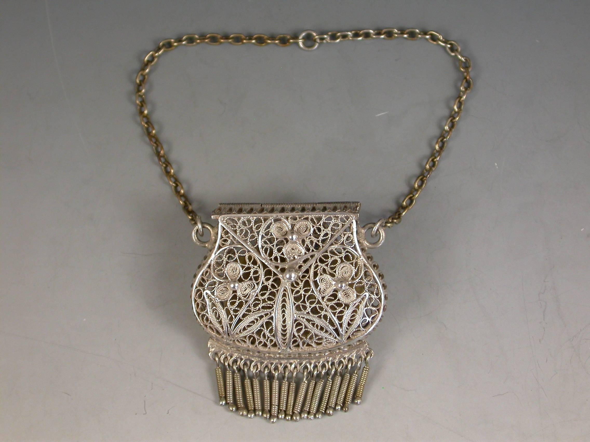 A good quality late 19th century silver filigree Chatelaine Purse Vinaigrette with attached suspension chain and pendant spring fringe, the hinged cover and body finely decorated with flower heads and scrolls.

Unmarked circa 1880

In good