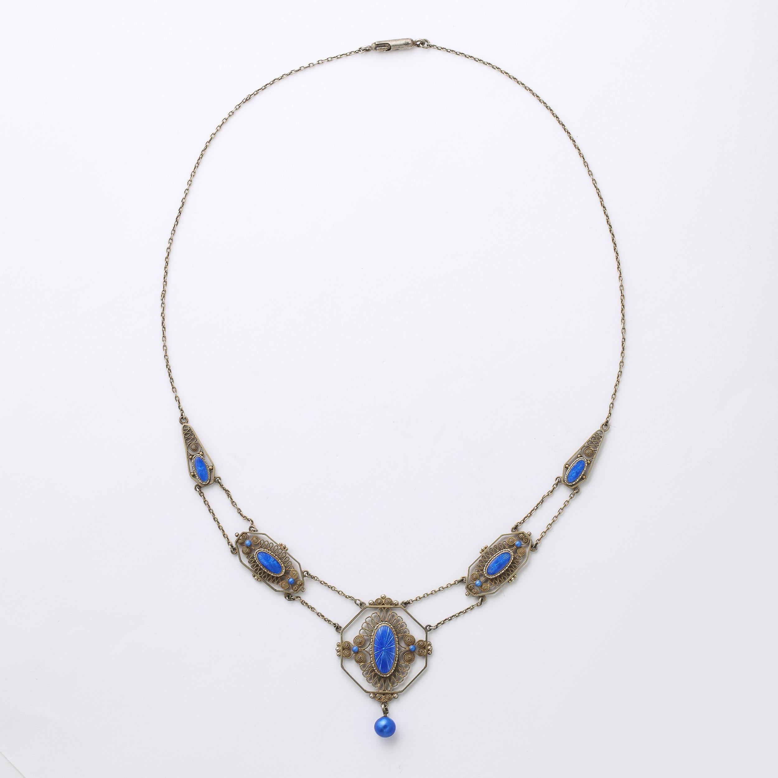 This Antique Edwardian swag design necklace features 5 cartouches set with a filigree design set with  blue guilloche enamel accents . This stunning necklace has a Renaissance revival feel . It is marked 830 s and is also fitted with the original