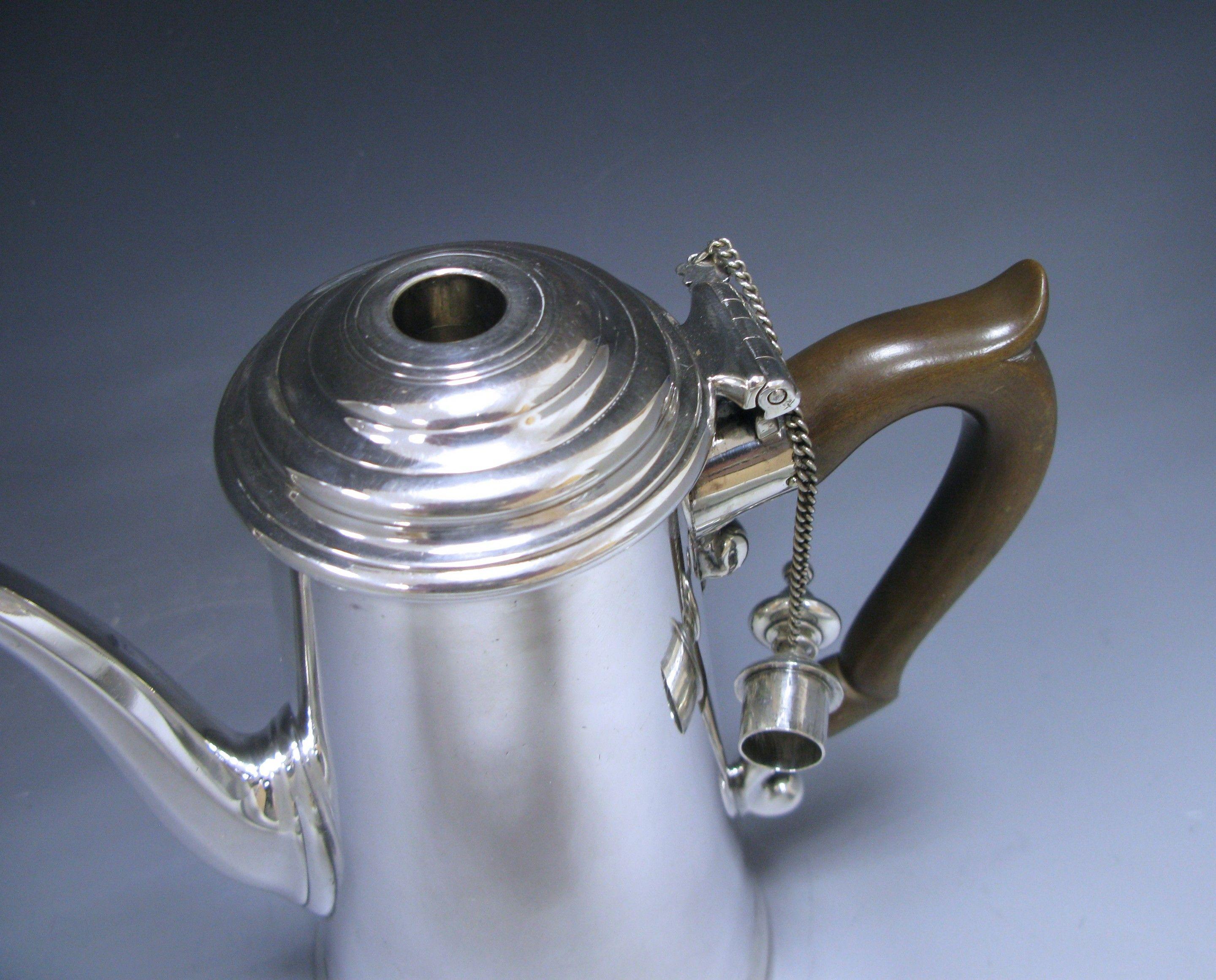 A superb antique silver George II chocolate pot with straight tapering sides and a simple wooden handle. The lid is detachable and is held in place by a pin and chain. The top finial is removable so that the chocolate can be stirred. To the front