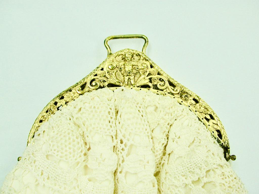 Antique silver gilt and cream lace evening handbag,dated 1913,chester
The silver gilt top is heavily cast decorated with a cherub each side,
flowers,scrolls, laurel and leafwork.
The clasp is sprung and inside there is a separate lining.
Any