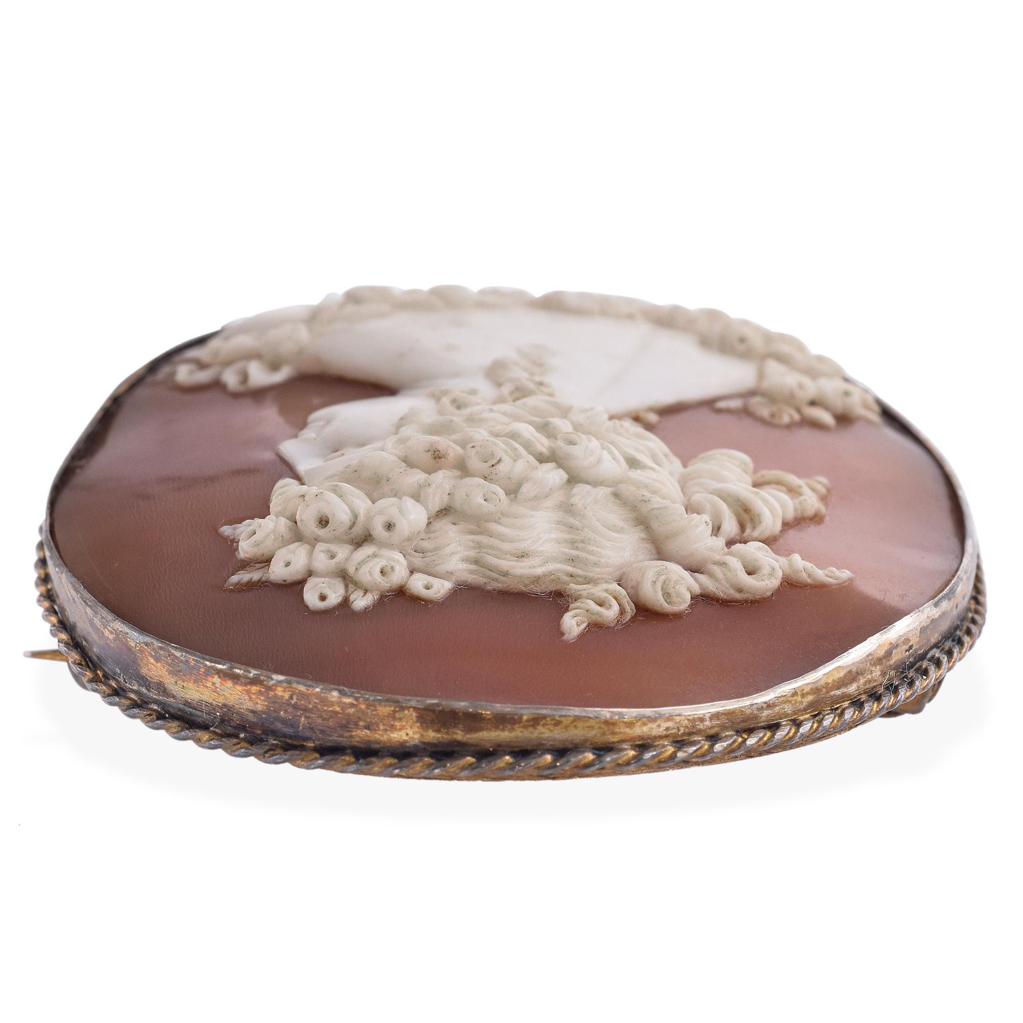 Questa antica spilla a cammeo raffigura Flora, la dea romana della primavera e dei fiori, immortalata in una graziosa vista posteriore con la testa girata di profilo. L'intaglio finemente dettagliato mette in mostra i capelli fluenti e i delicati