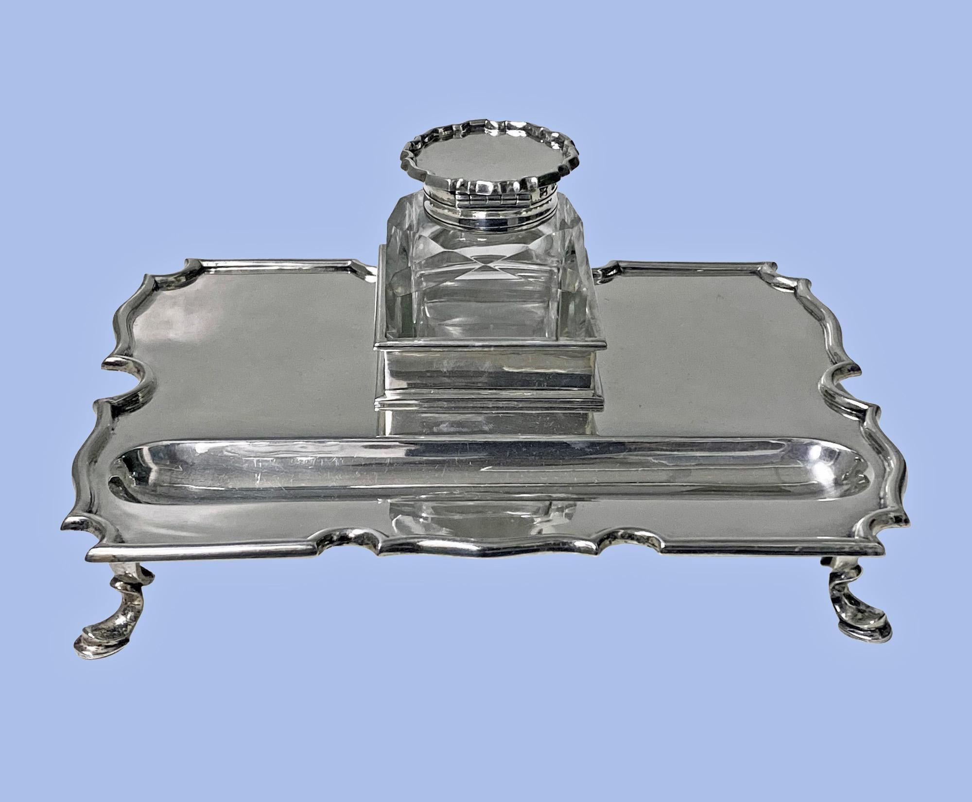 Antique Silver Inkstand Inkwell, London 1899 Goldsmiths and Silversmiths Co. Plain rectangular form on four turned feet, shaped chippendale like border, well section for pen and square facetted glass inkwell, hinged silver cover. Measures: 7.25 x