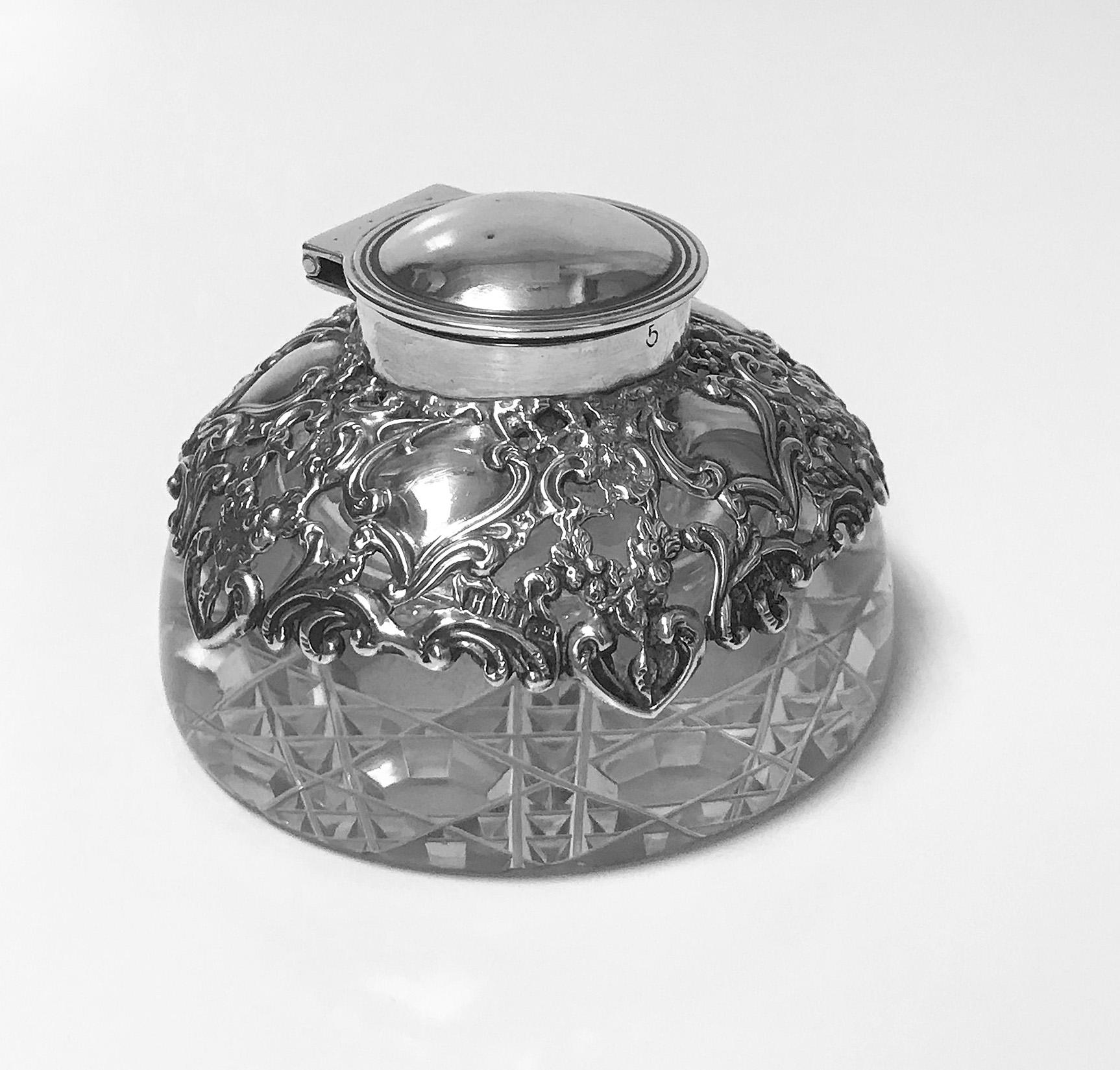 Antique silver and glass inkwell paperweight, Birmingham, 1900 H. Matthews. The inkwell with pierced foliage and vacant cartouche silver decoration, plain hinged thread surround cover all on plain glass body with unusual octagonal and diamond square